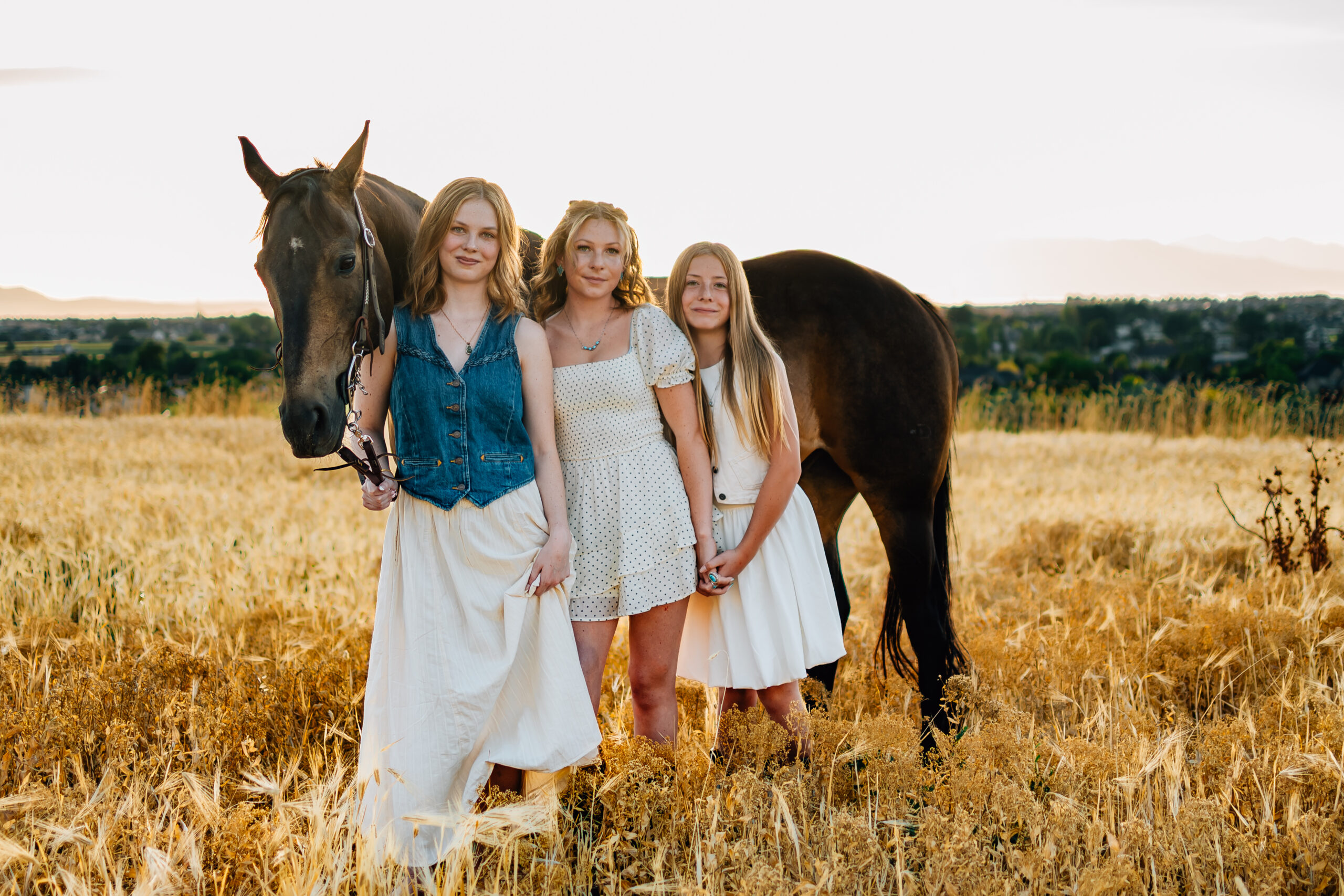 Just some girls with a horse. As the sun is setting three sisters stand in front of a horse smiling on.