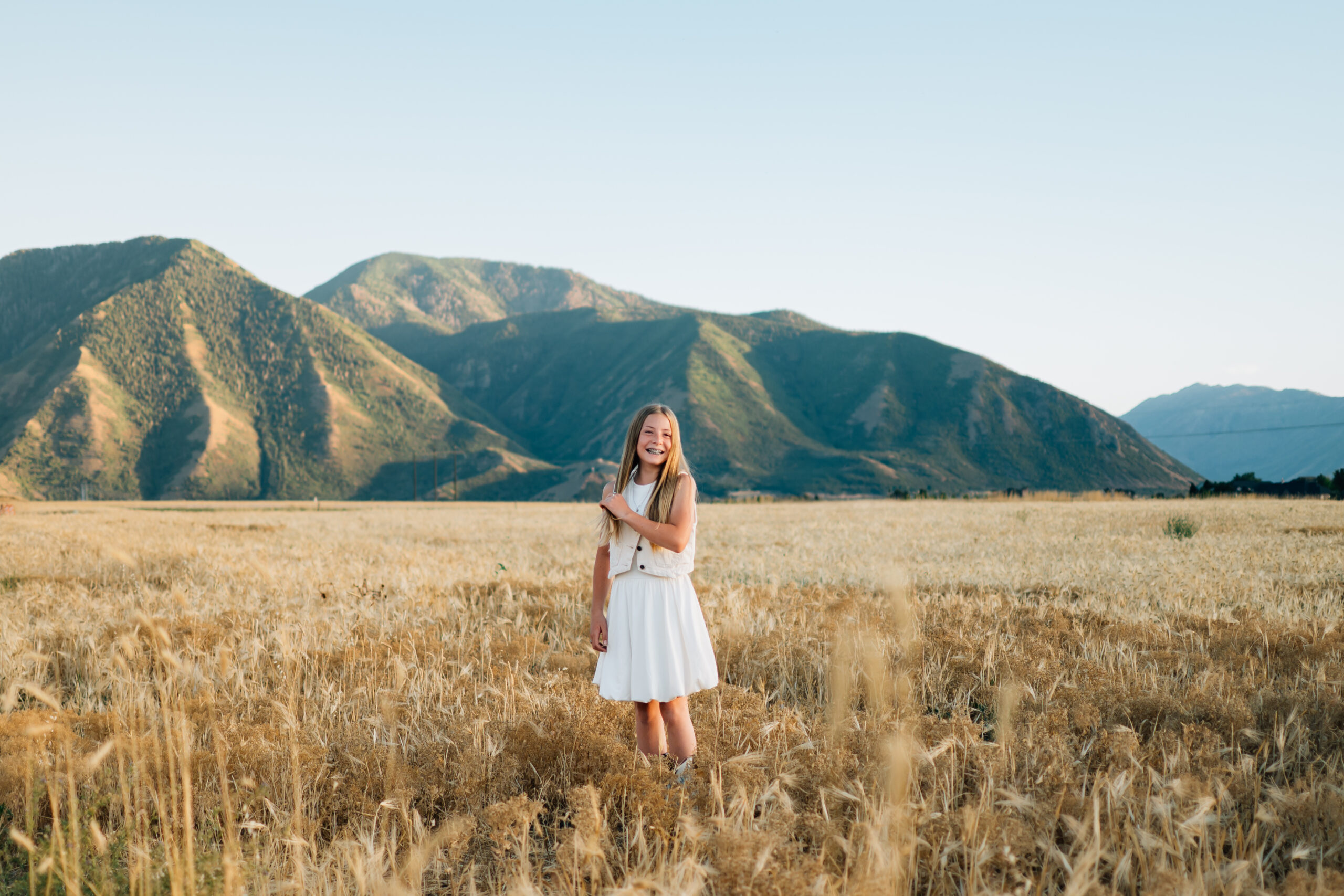 A girl fixes her hair as she smiles for the photo.