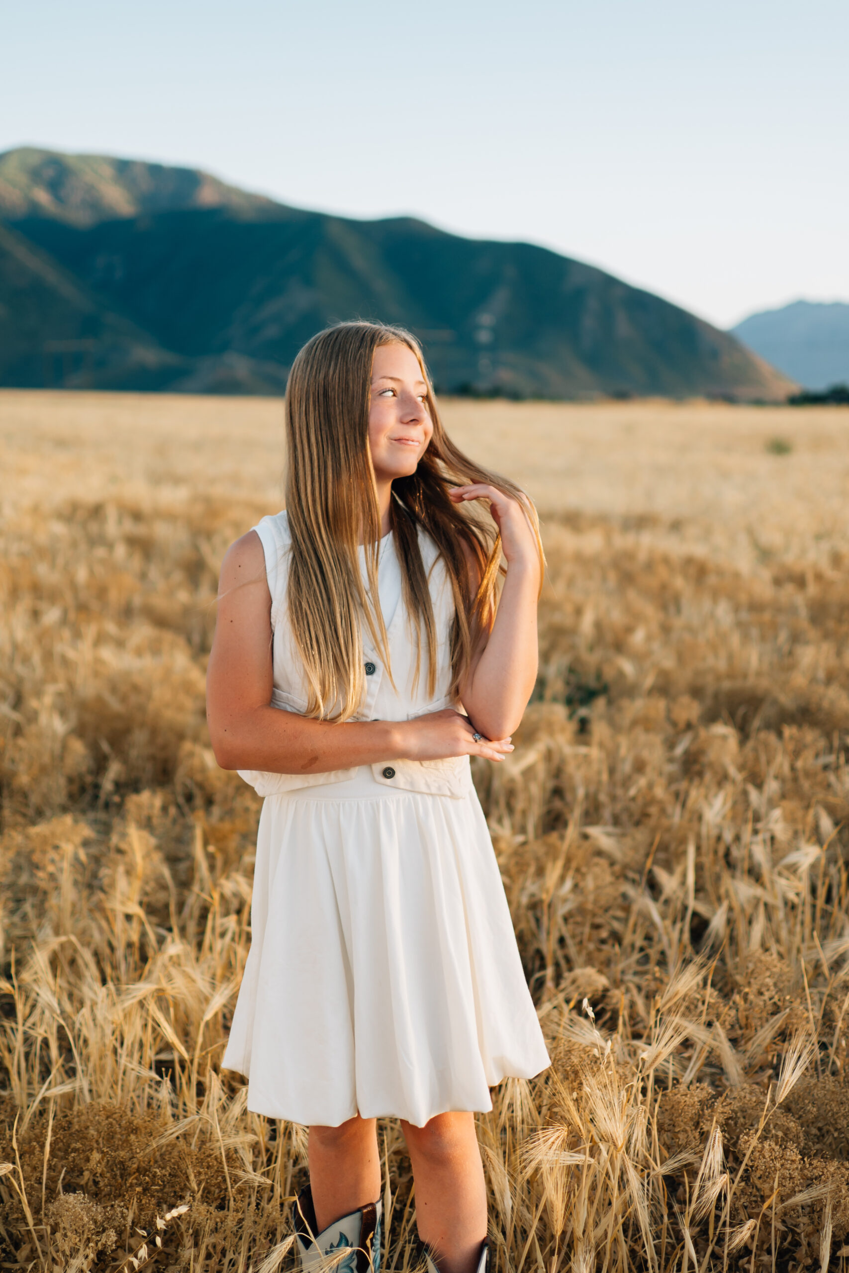 A girl plays with her hair as she watches the sun set.