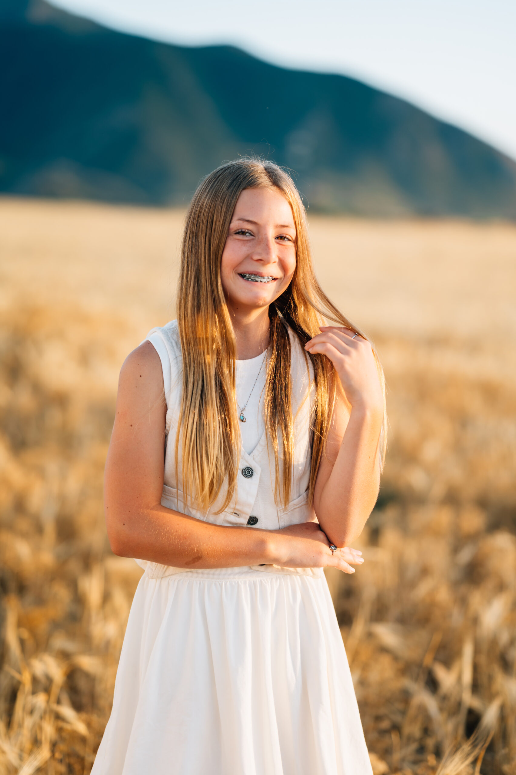 A girl fixes her hair as she smiles for the photo.