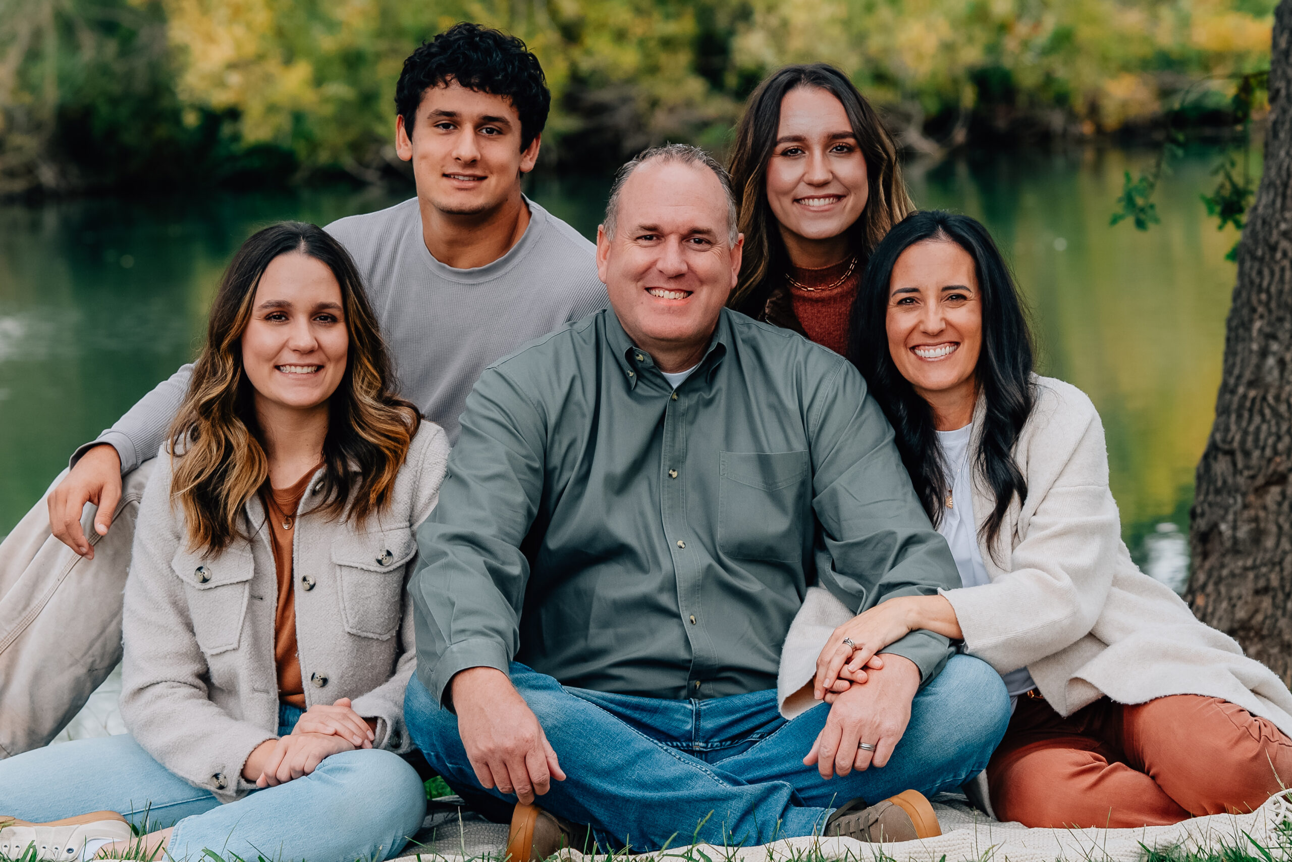 Parents and adult children sitting together by the lake during a Lodi CA family session