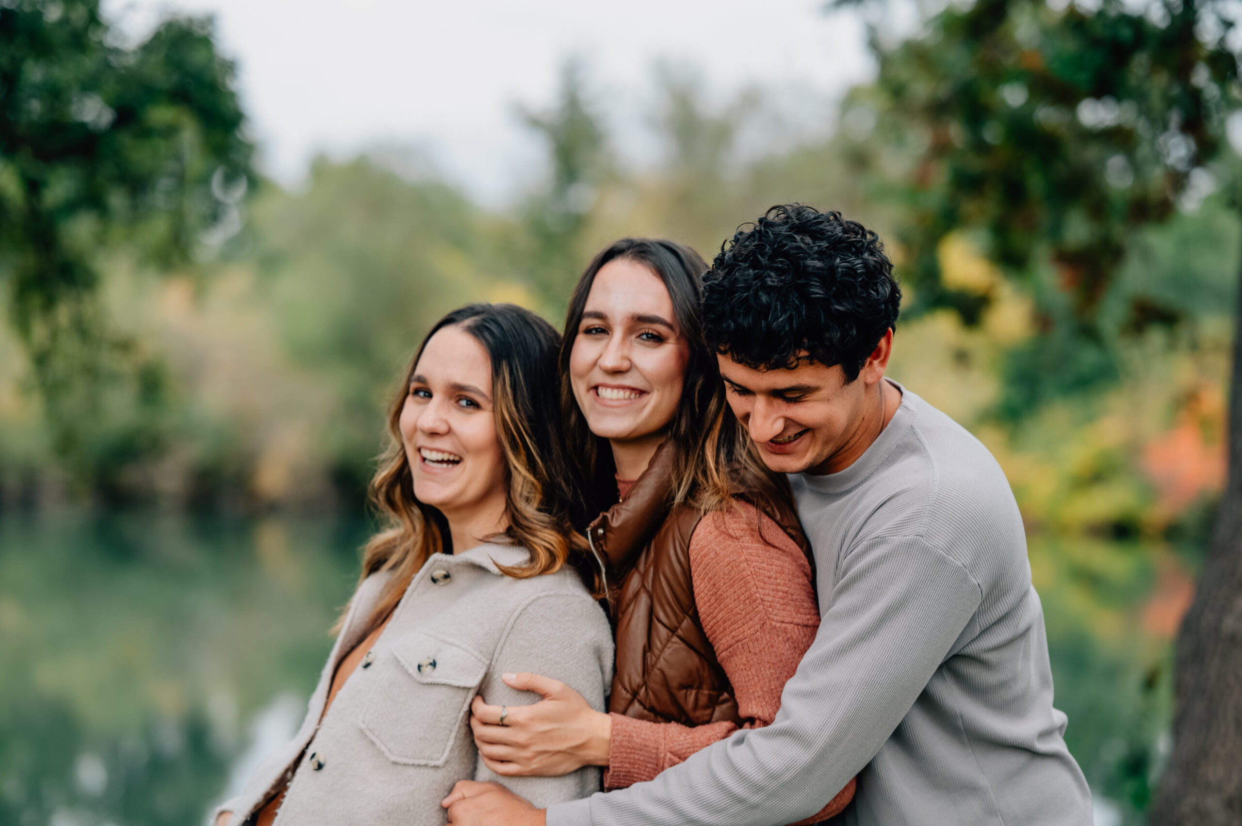 Three siblings hugging and laughing during a family photo session at Lodi Lake