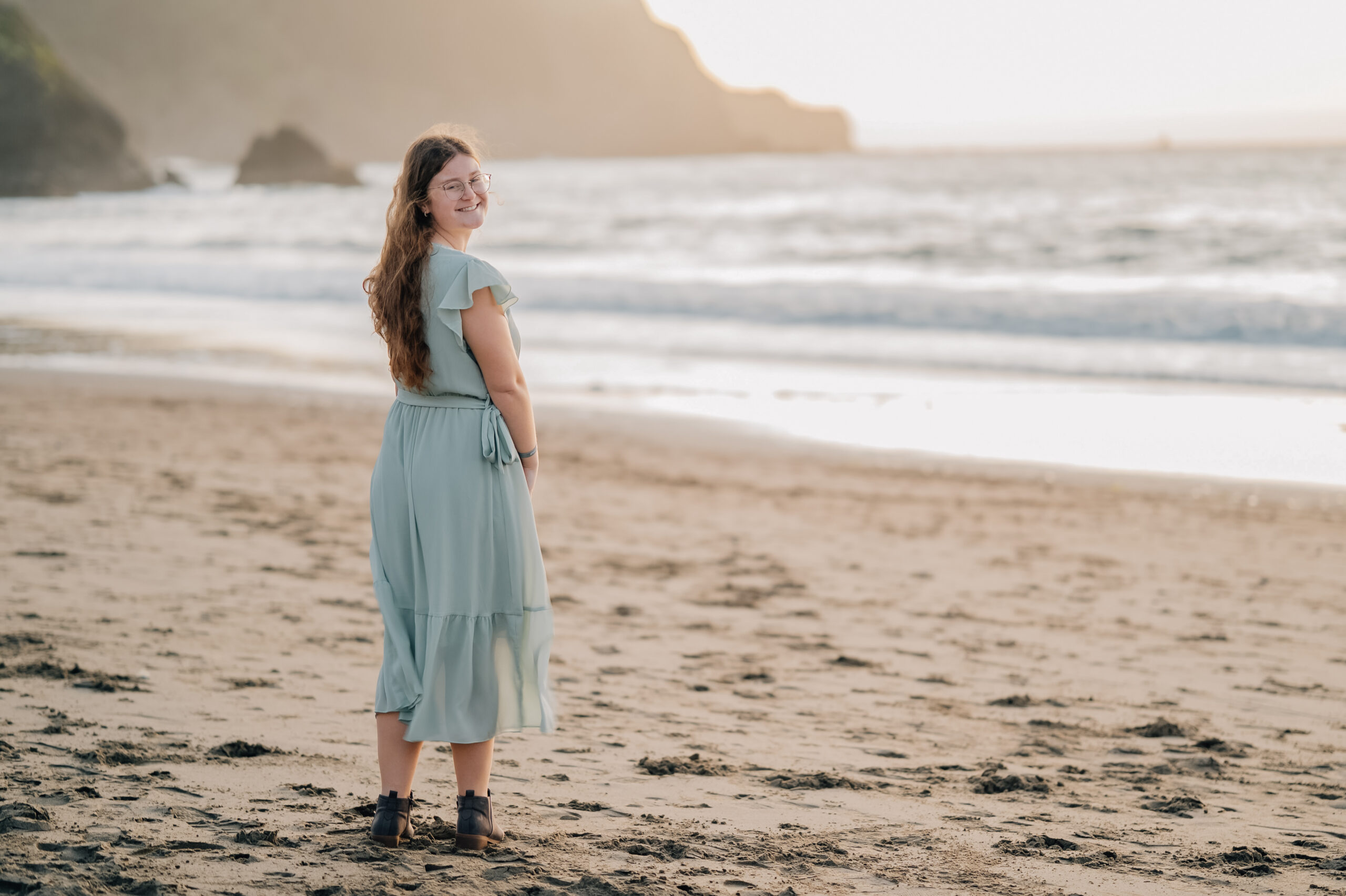 Senior portrait on Baker Beach at golden hour with soft ocean background.