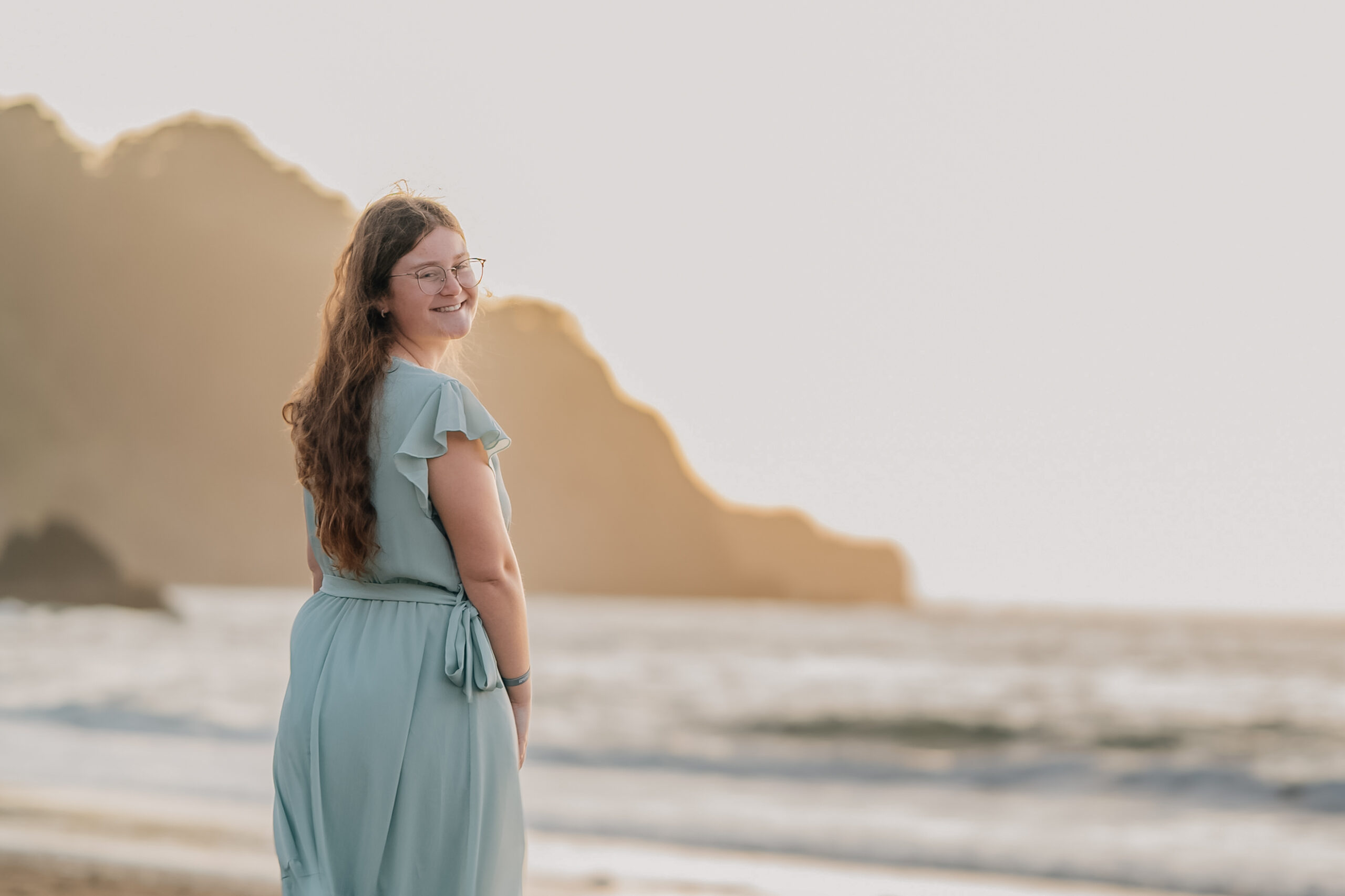 Senior portrait on Baker Beach at golden hour with soft ocean background.