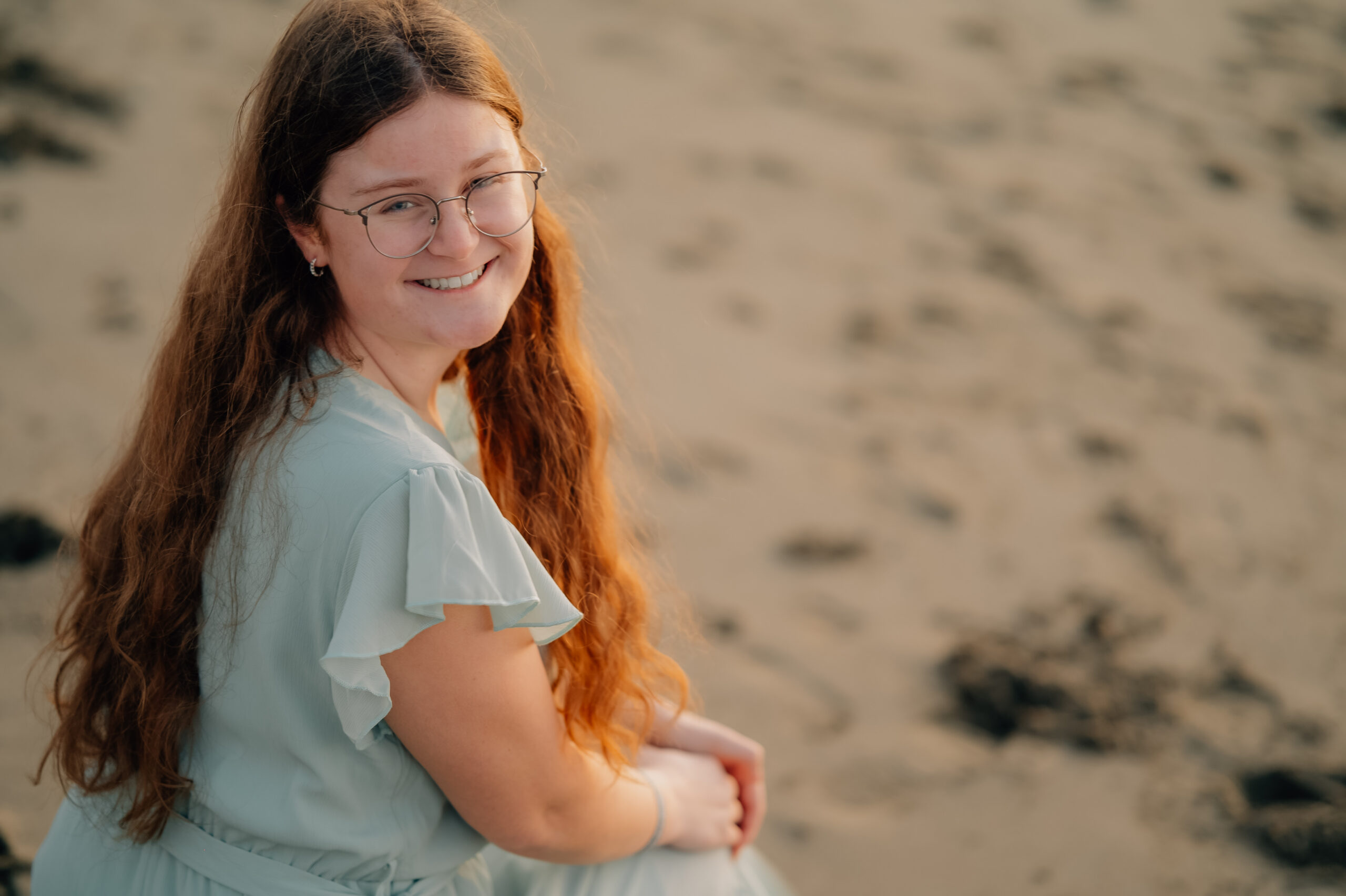 Senior portrait on Baker Beach at golden hour with soft ocean background.