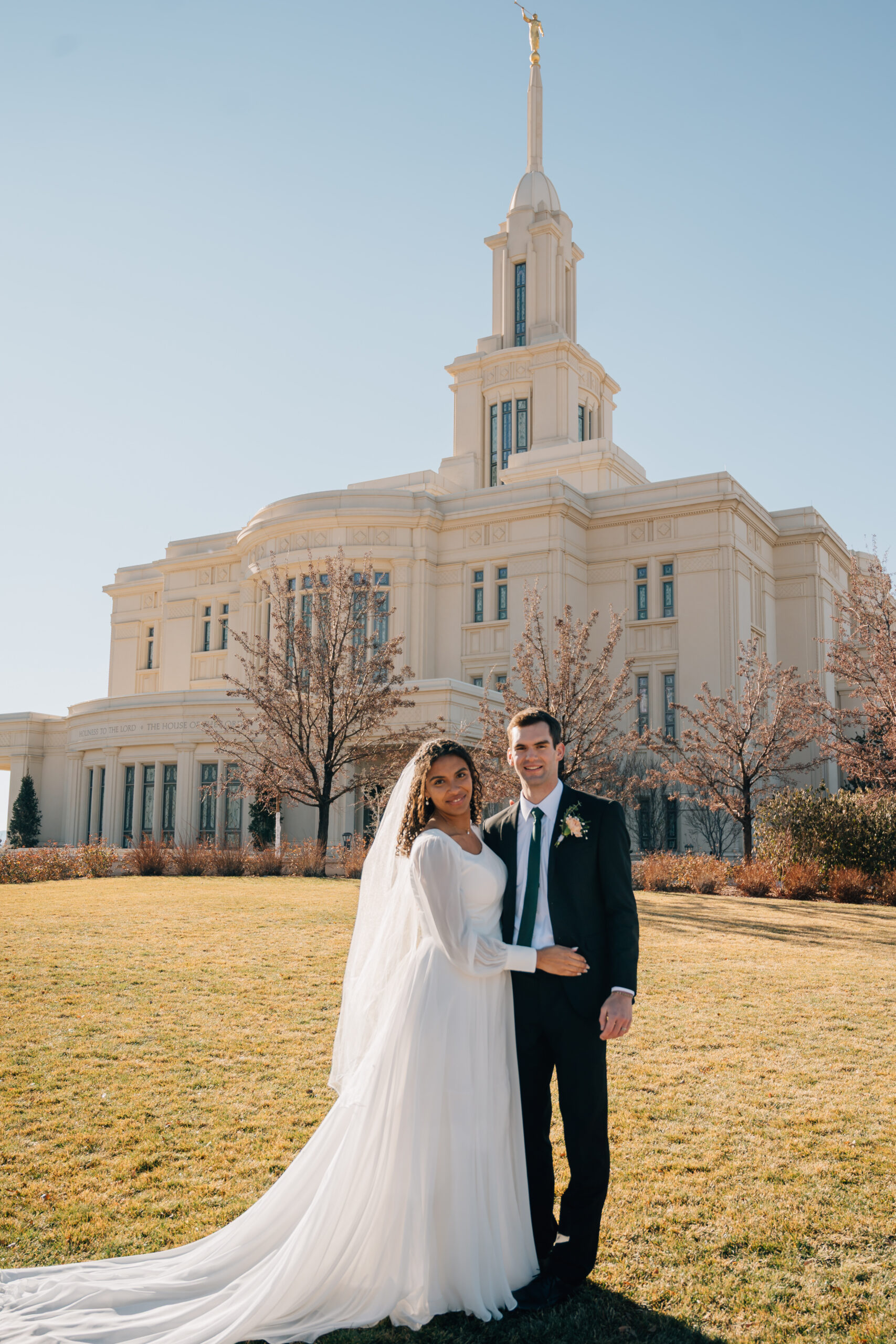 Newlywed couple smiling together outside the Payson Utah Temple