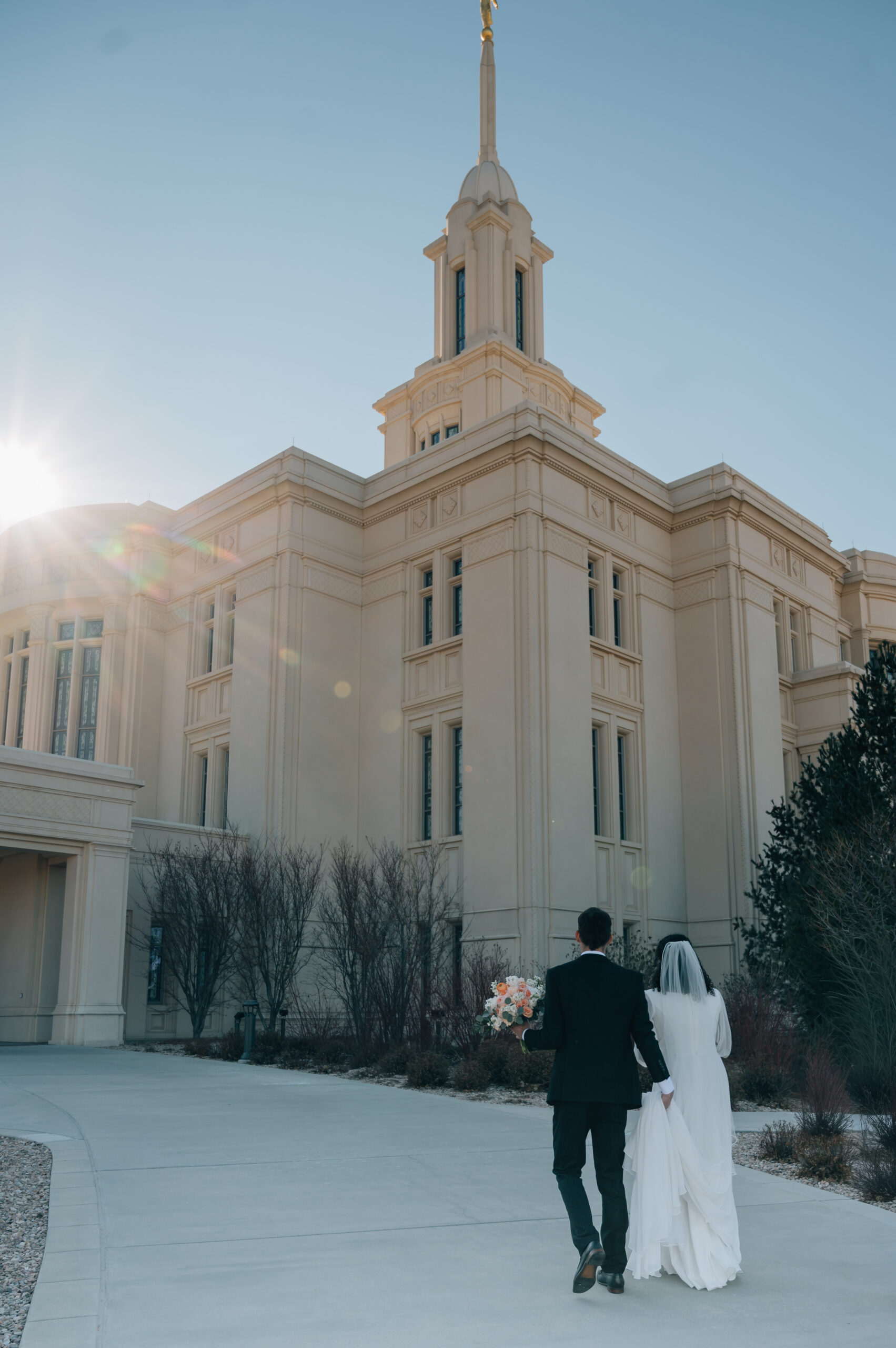 Newlywed couple walking together outside the Payson Utah Temple