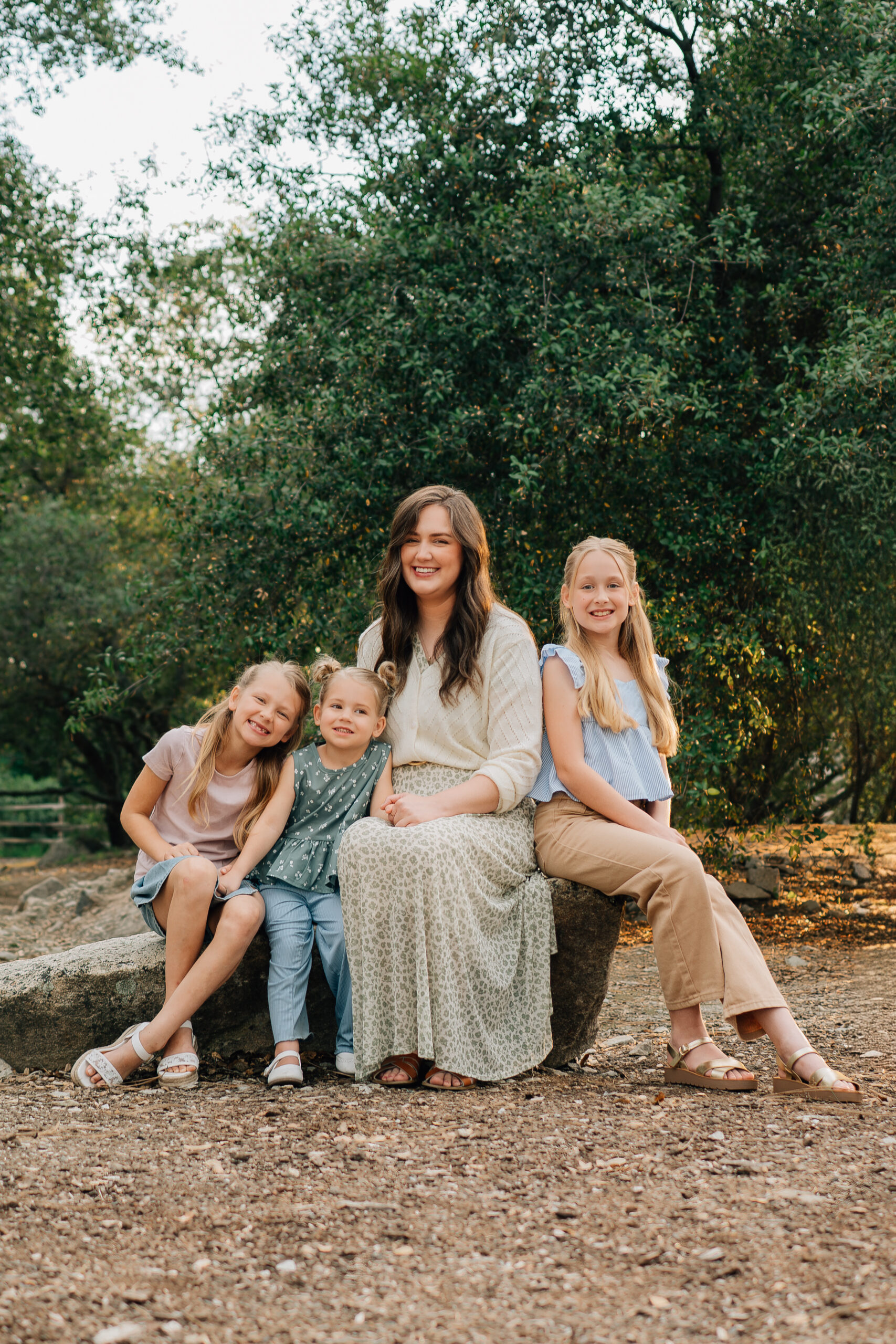 Mother sitting with her three daughters cuddled close during a warm, connected family photo session