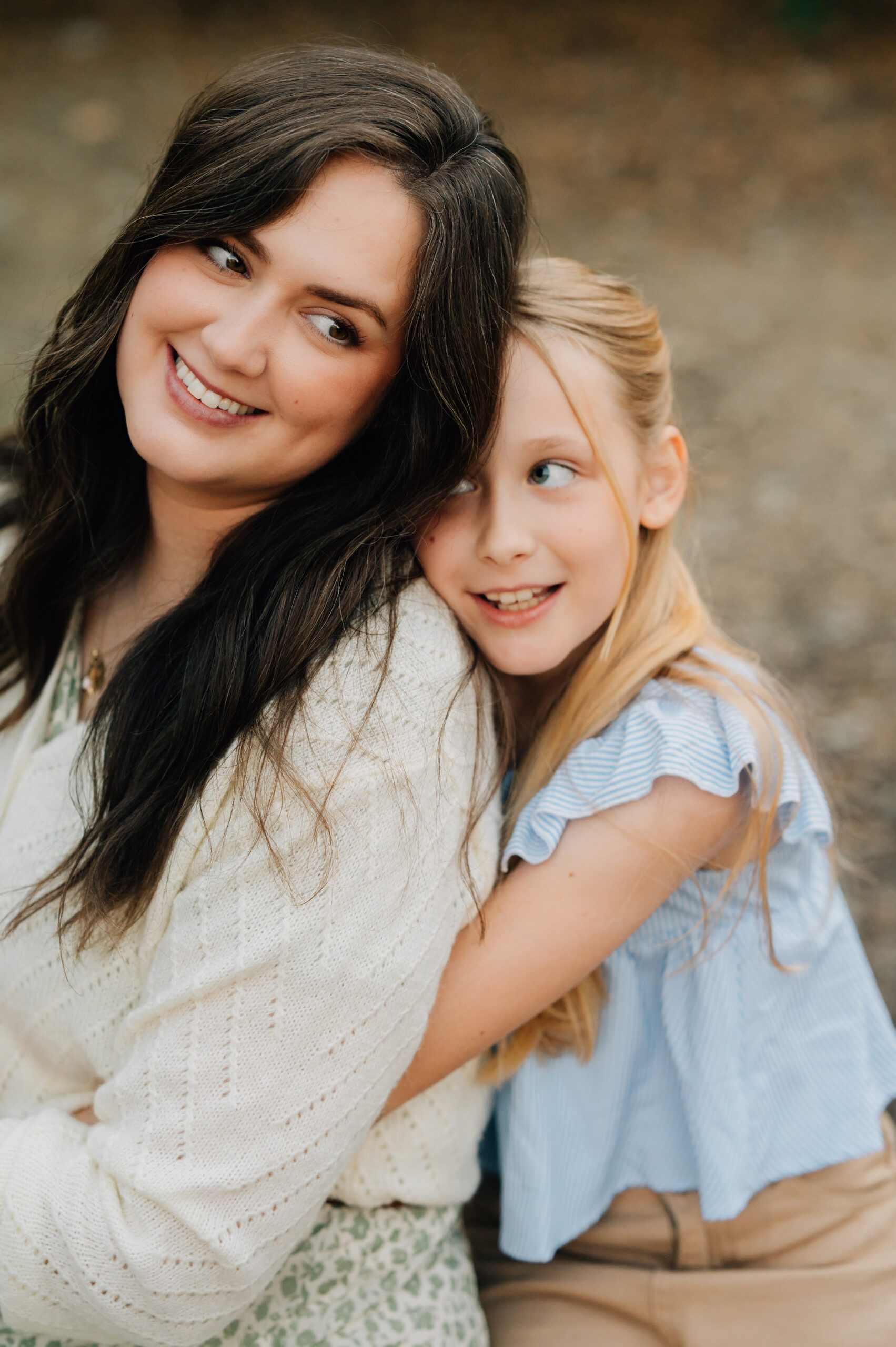 Close-up portrait of a young girl hugging on her Mom during a playful outdoor family session