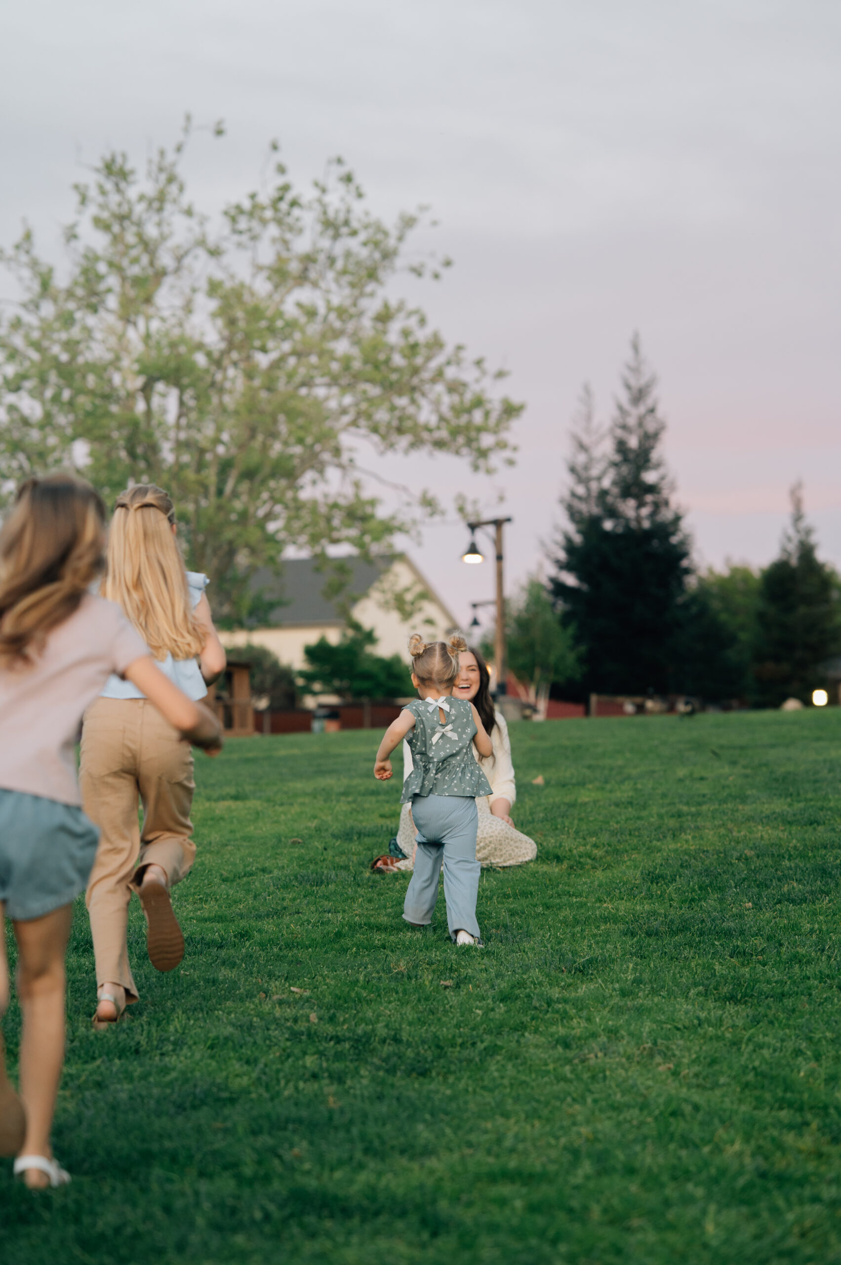 Three girls running toward their mom in a joyful, candid moment during a family session in Rocklin CA