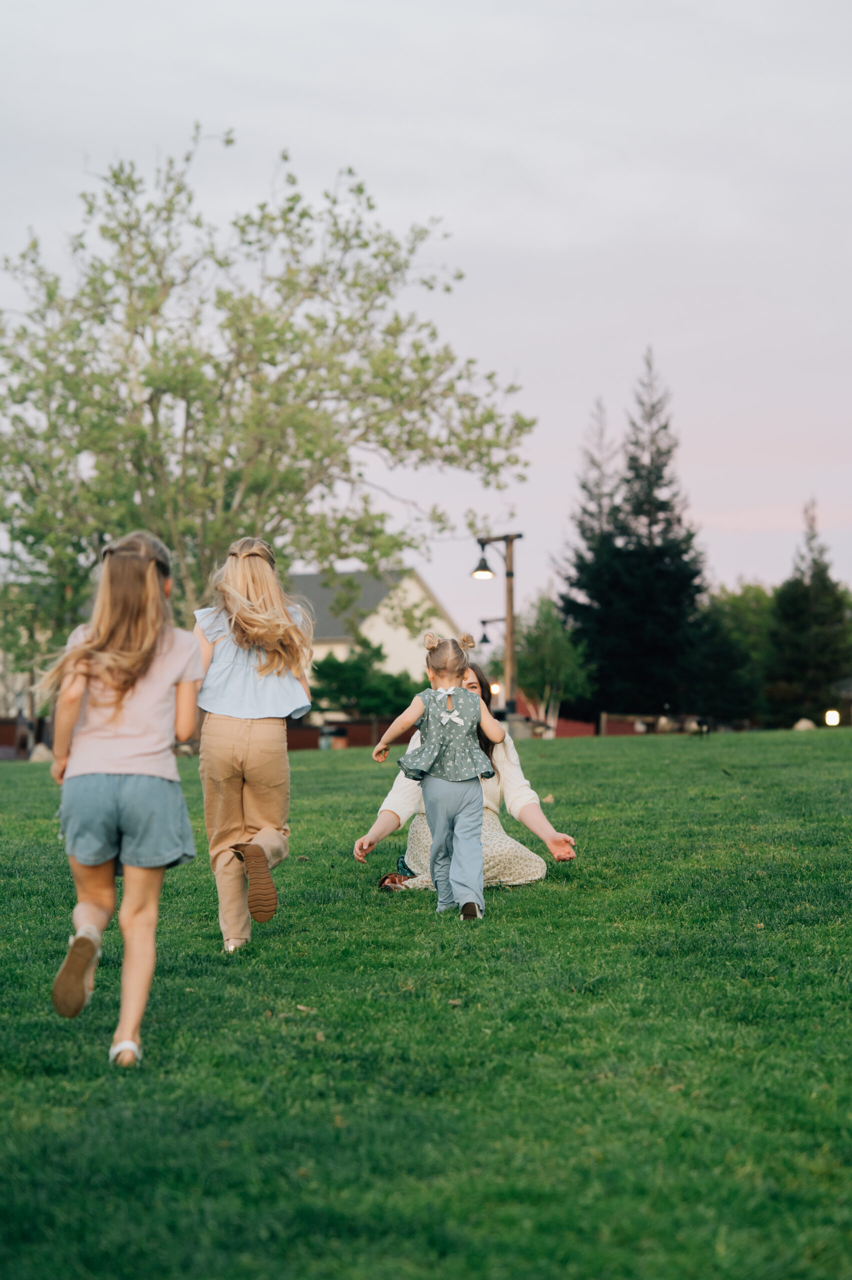 Three girls running toward their mom in a joyful, candid moment during a family session in Rocklin CA