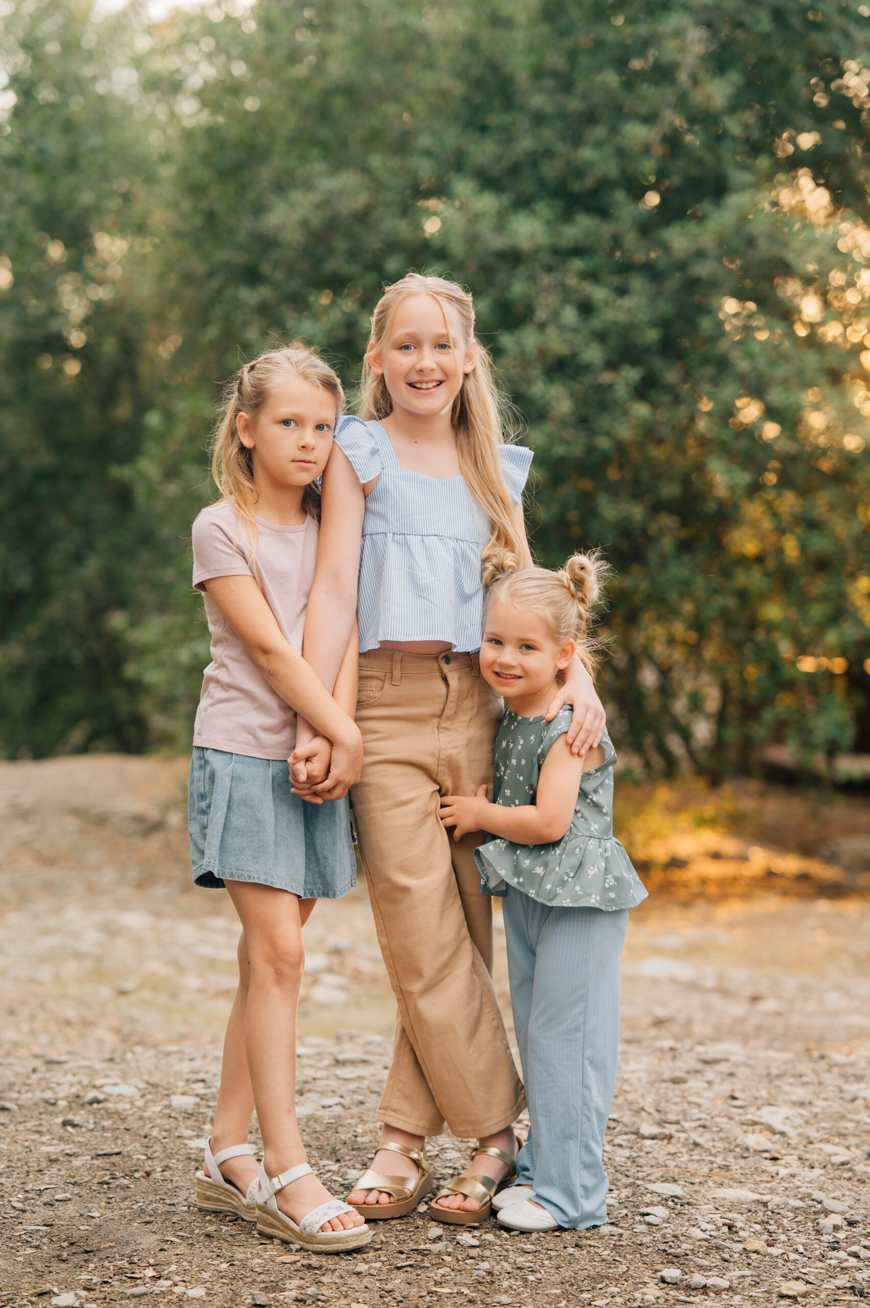 Three sisters holding hands and cuddling up during a golden hour family session in Northern California