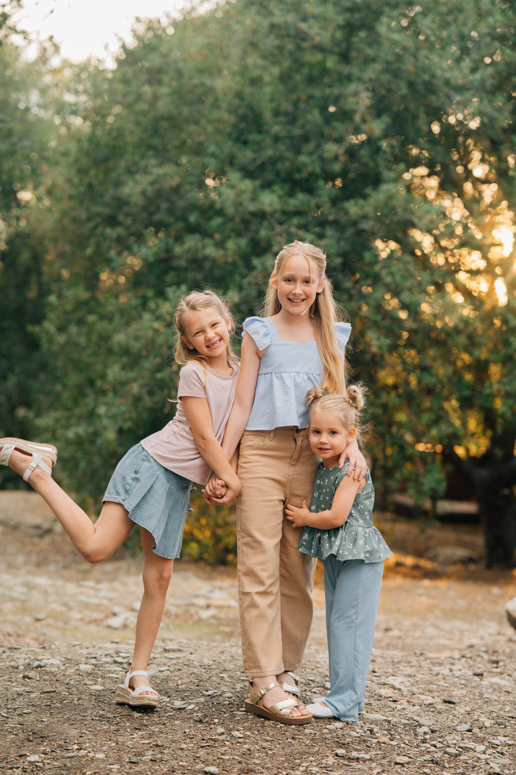 Three sisters holding hands and cuddling up during a golden hour family session in Northern California