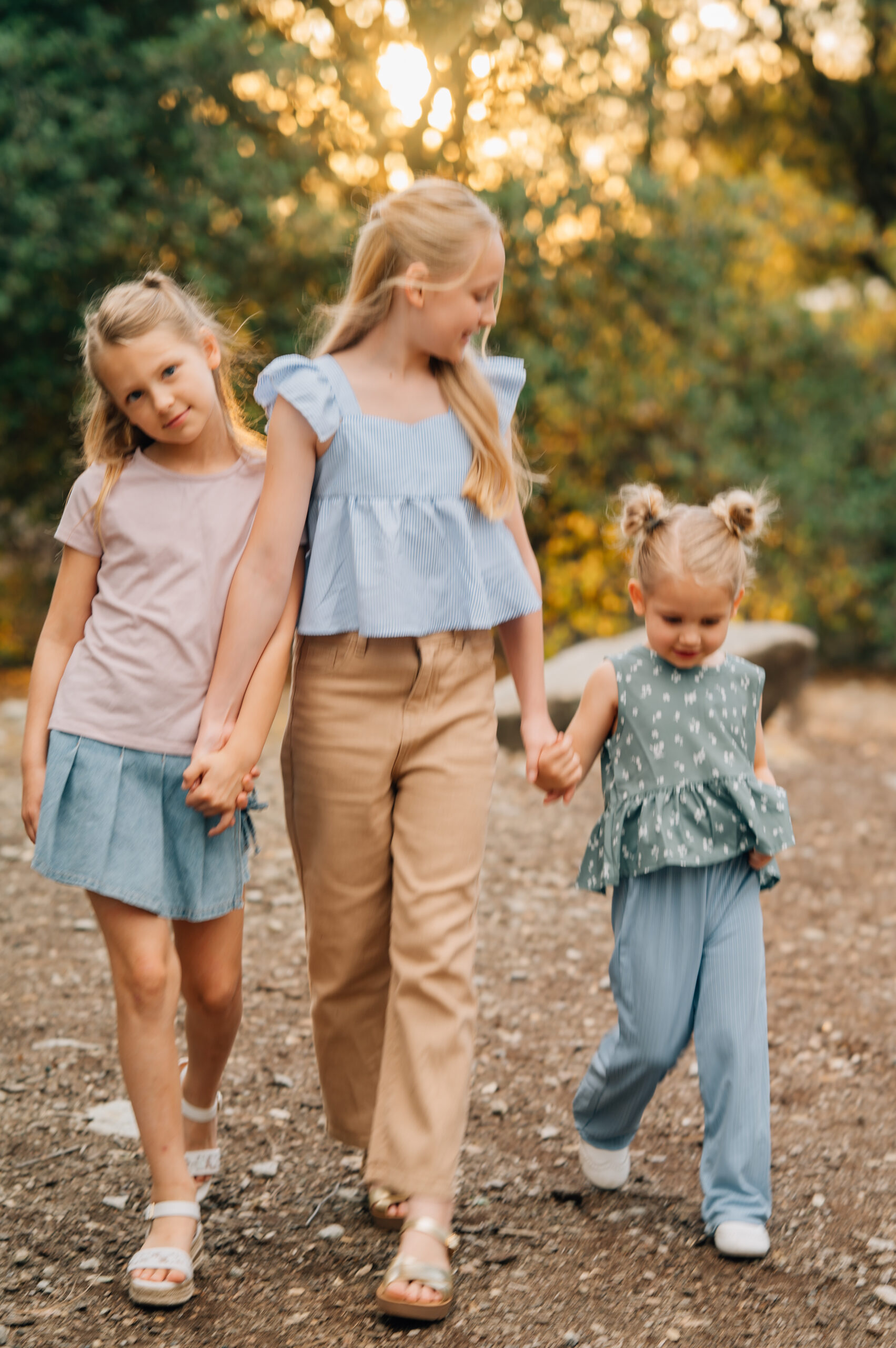 Three sisters walking hand in hand during a candid family photography session outdoors