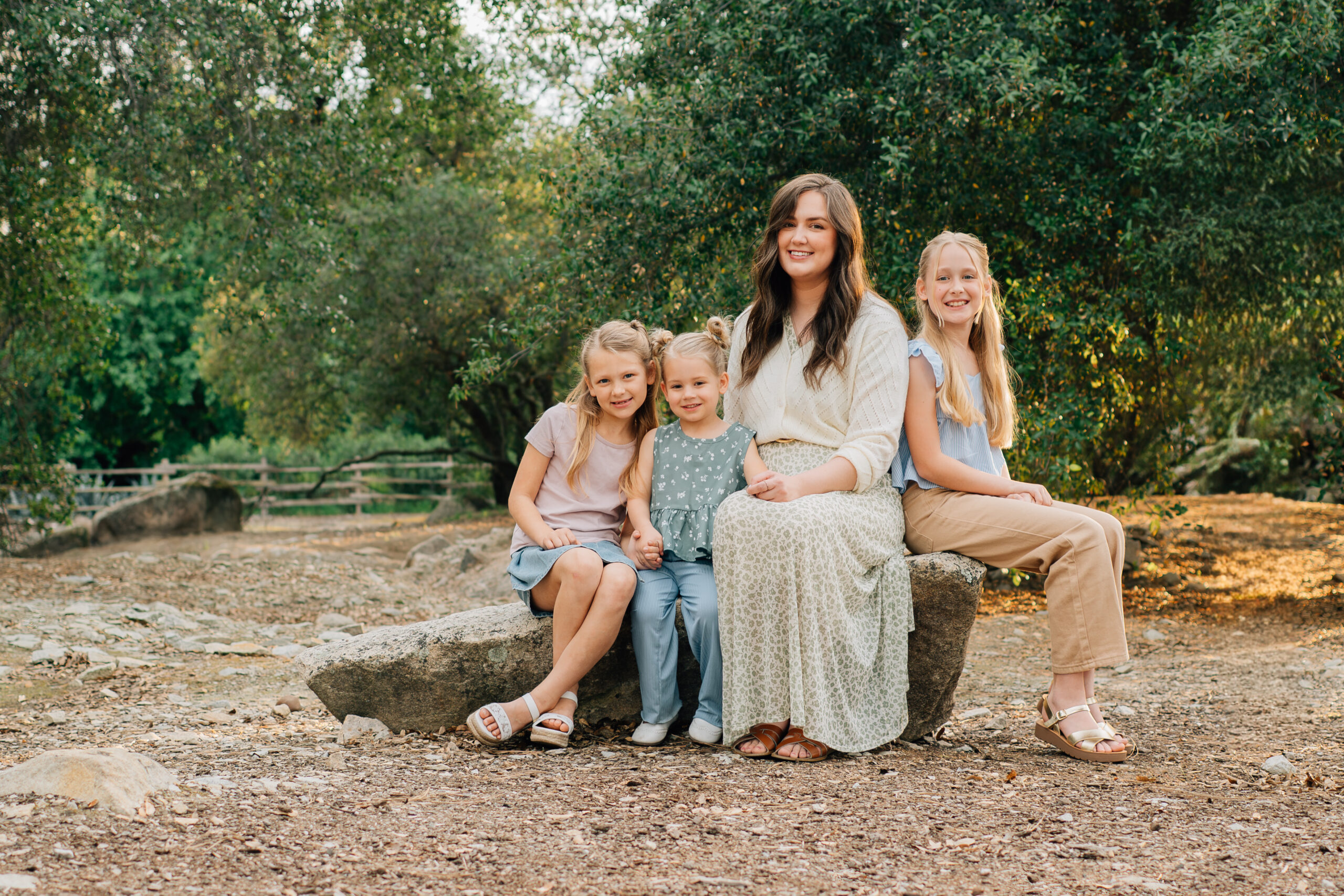 Mother sitting with her three daughters cuddled close during a warm, connected family photo session