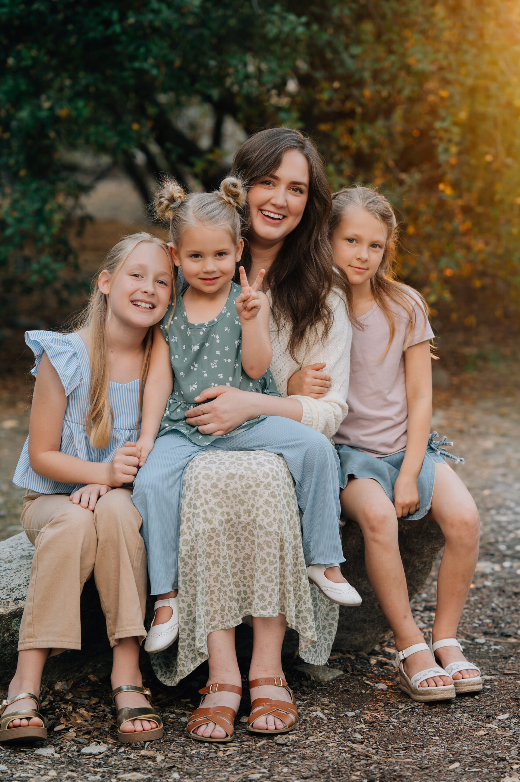 Mother sitting with her three daughters cuddled close during a warm, connected family photo session