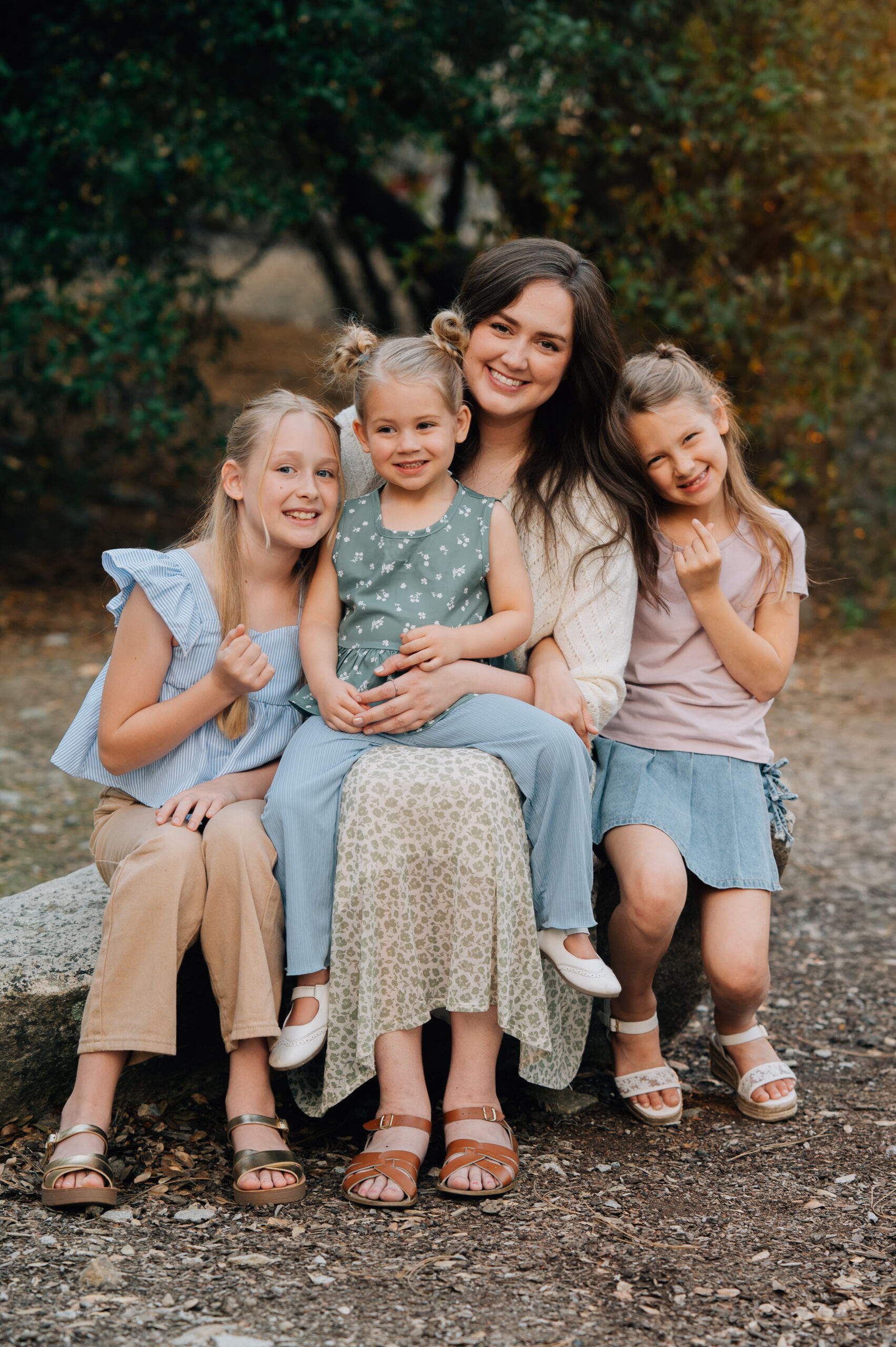 Mother sitting with her three daughters cuddled close during a warm, connected family photo session