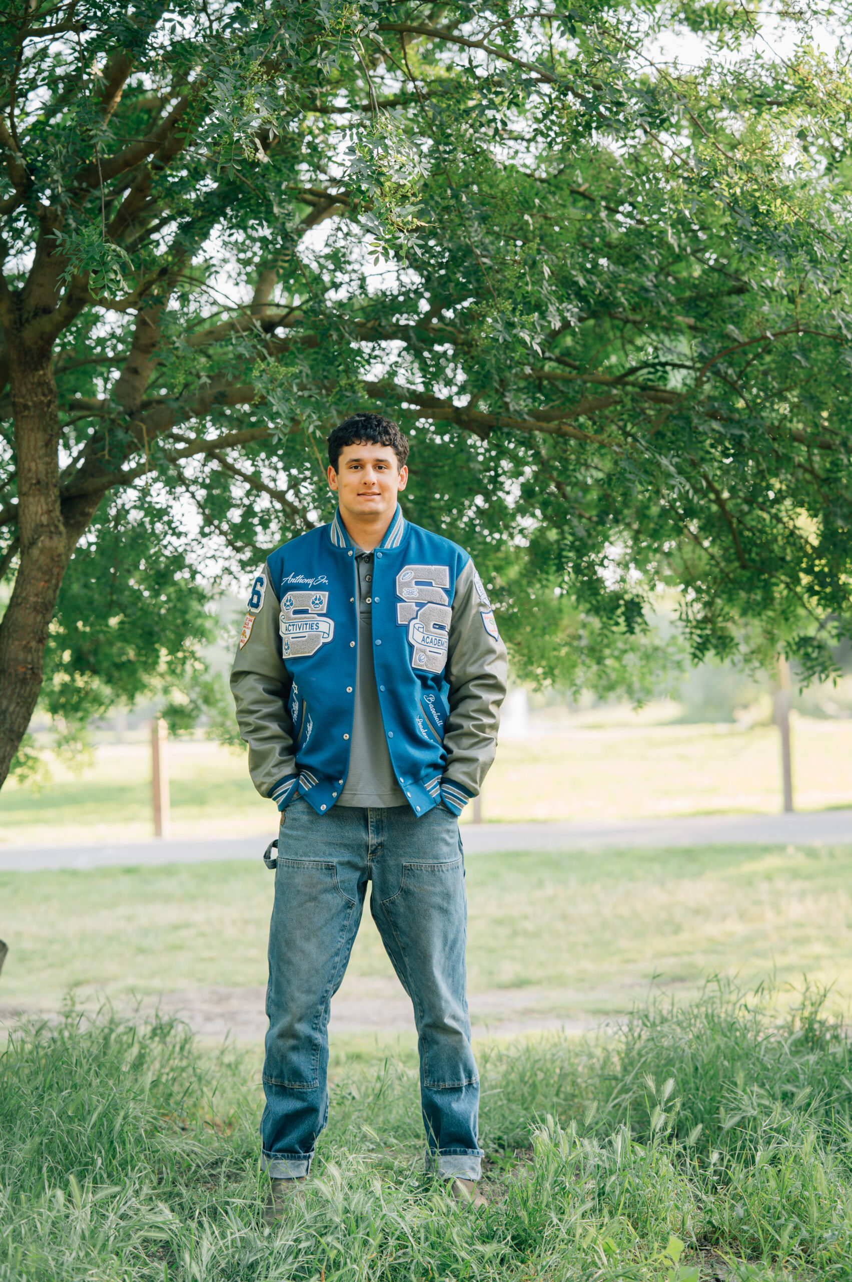 Senior boy standing beneath a tree at Shumway Oak Grove Park in Stockton 