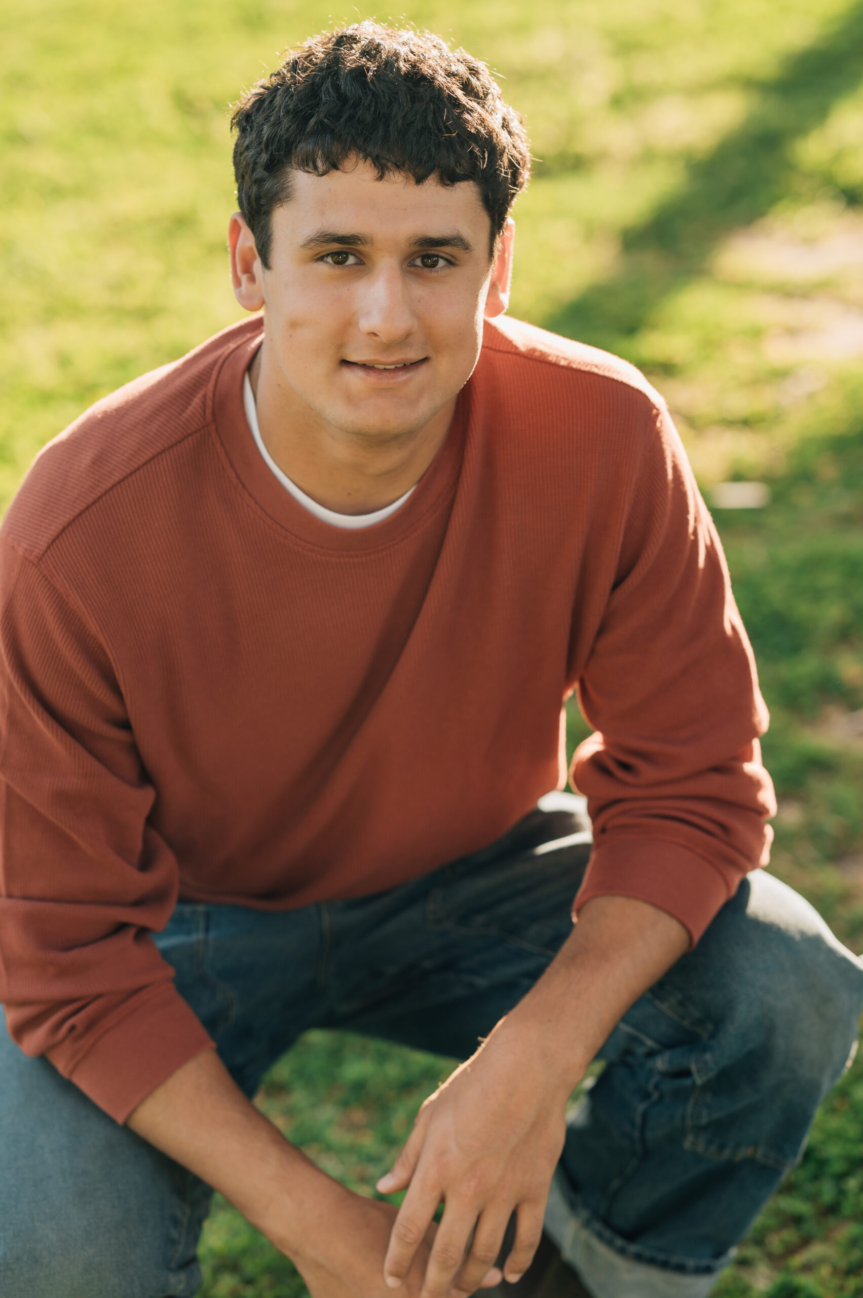 Senior boy crouching down at Shumway Oak Grove Park in Stockton 