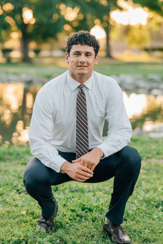 Senior boy crouching down at Shumway Oak Grove Park in Stockton 