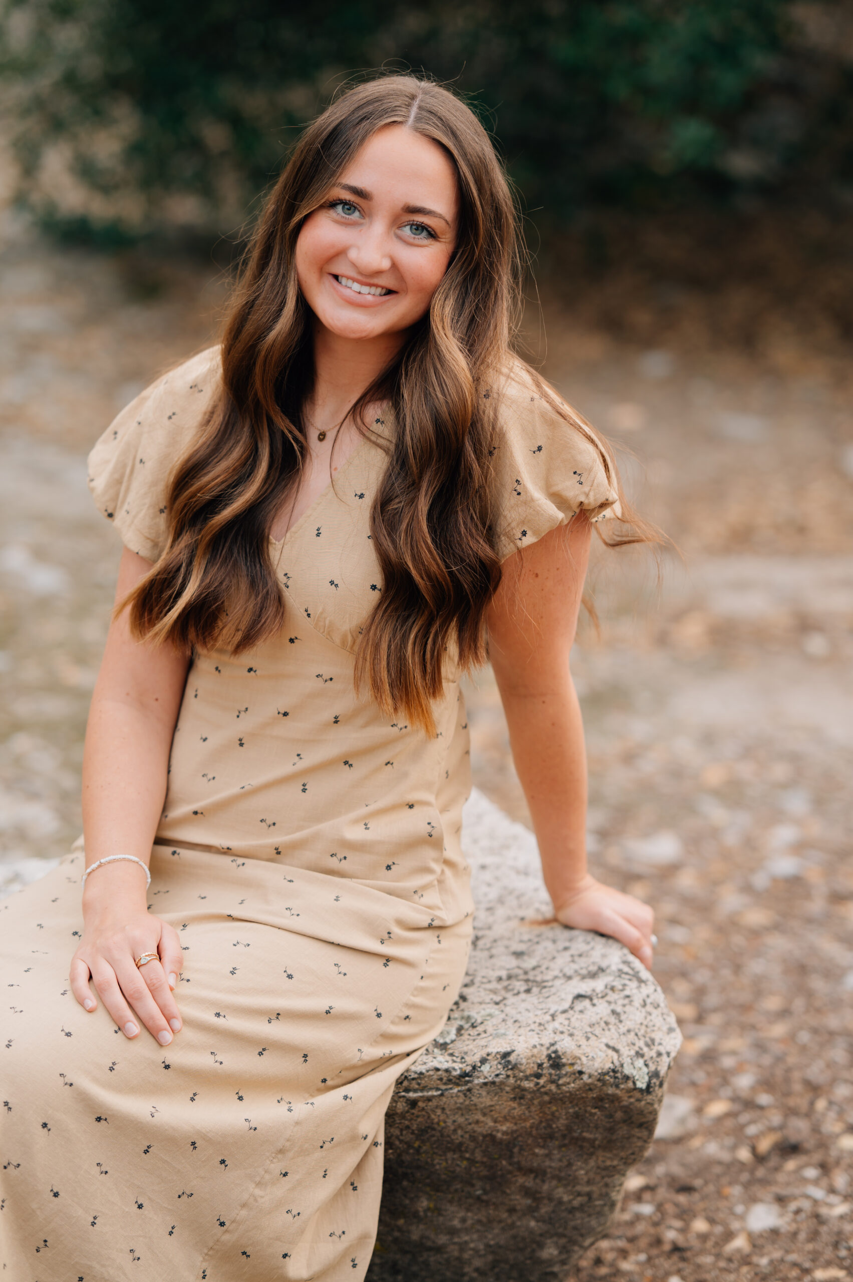 Senior girl smiling while seated on large rock at Quarry Park Adventures