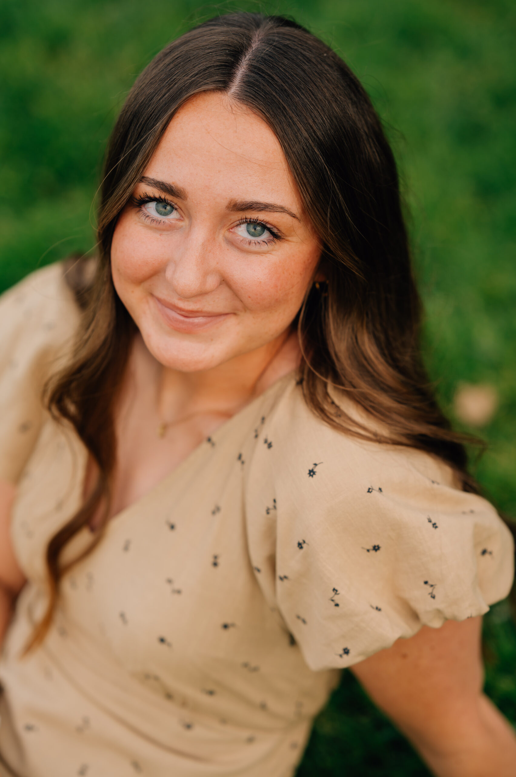 Close-up outdoor portrait of smiling senior girl with long brown hair and blue eyes