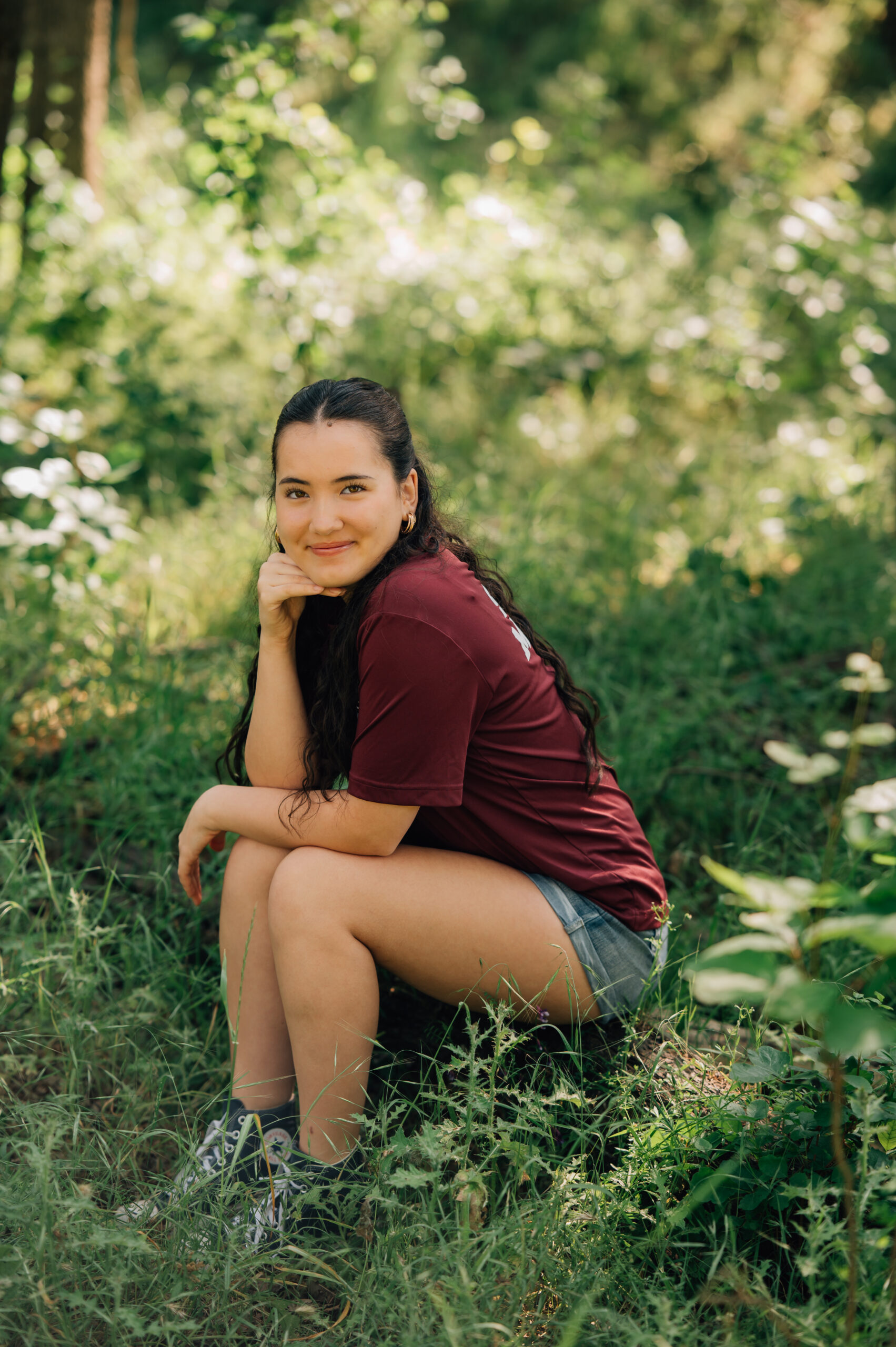 High school senior sitting in tall grass during outdoor portrait session in Rocklin