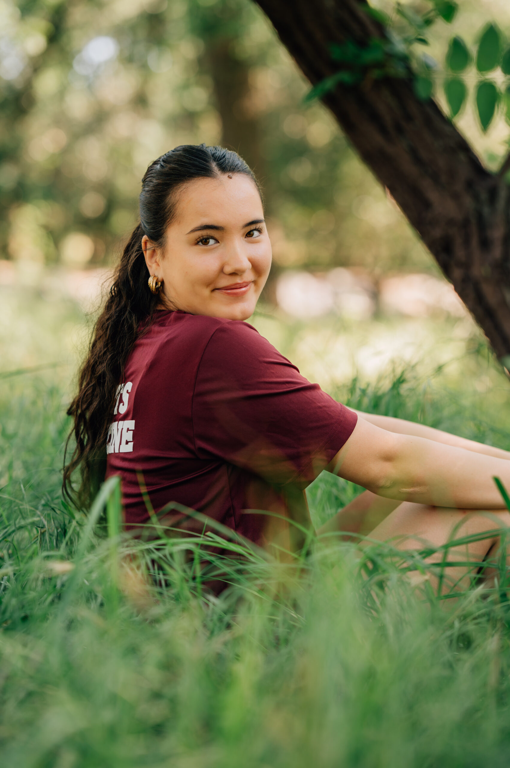 High school senior sitting in tall grass during outdoor portrait session in Rocklin