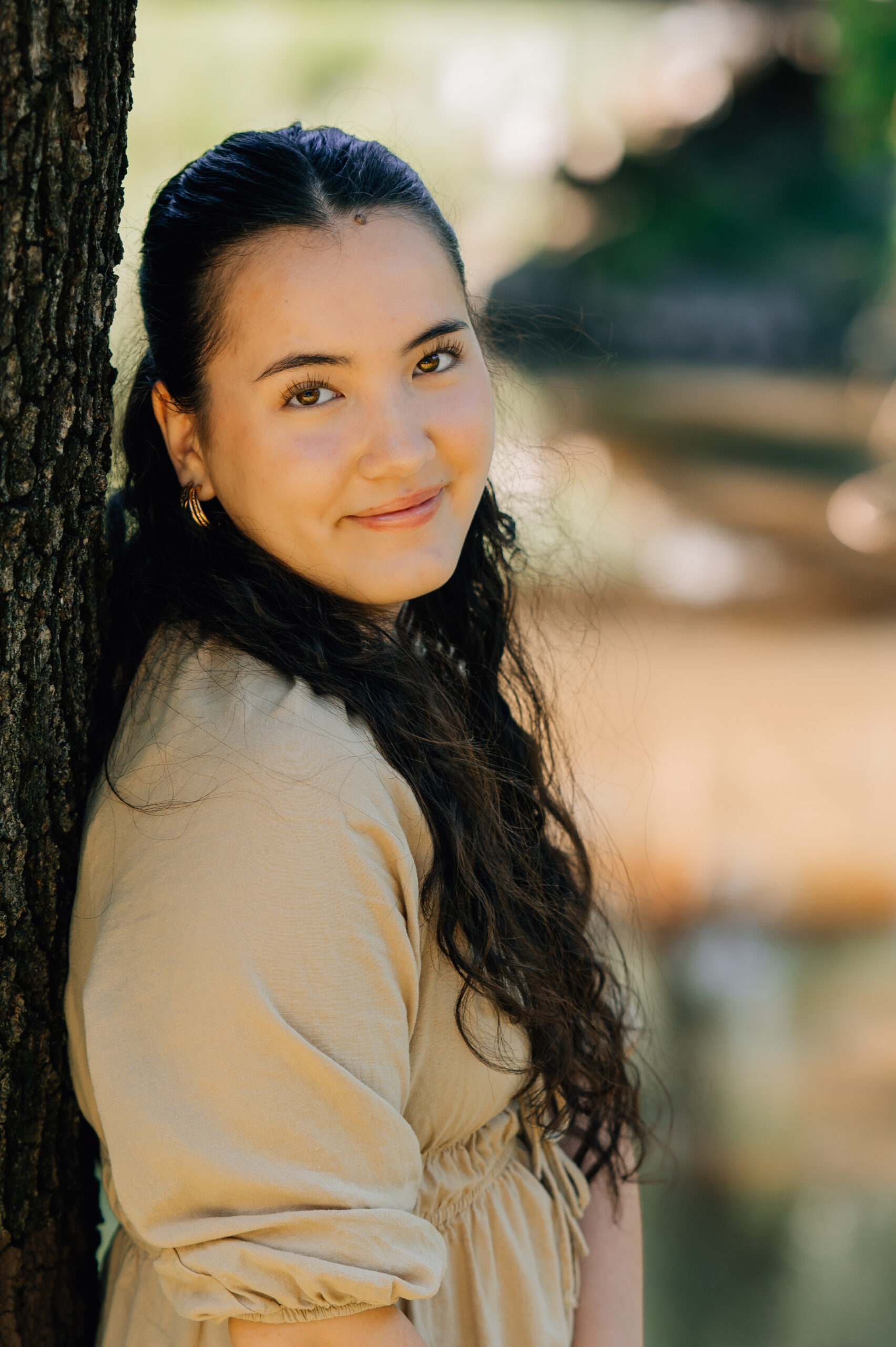 Senior portrait in soft neutral dress beside creek in Rocklin California