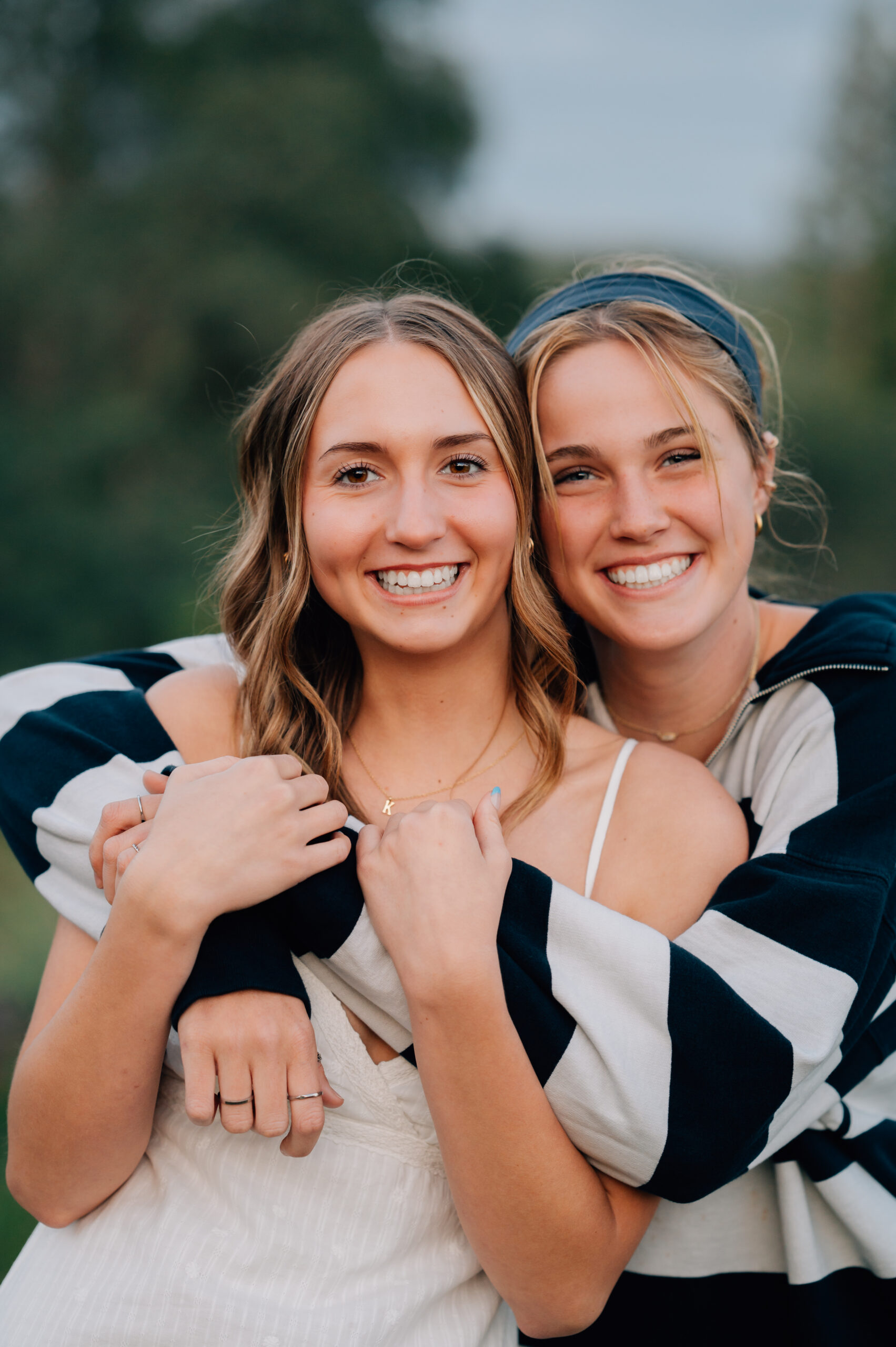 High school graduate smiling with her bestie during outdoor senior portraits in Penryn.