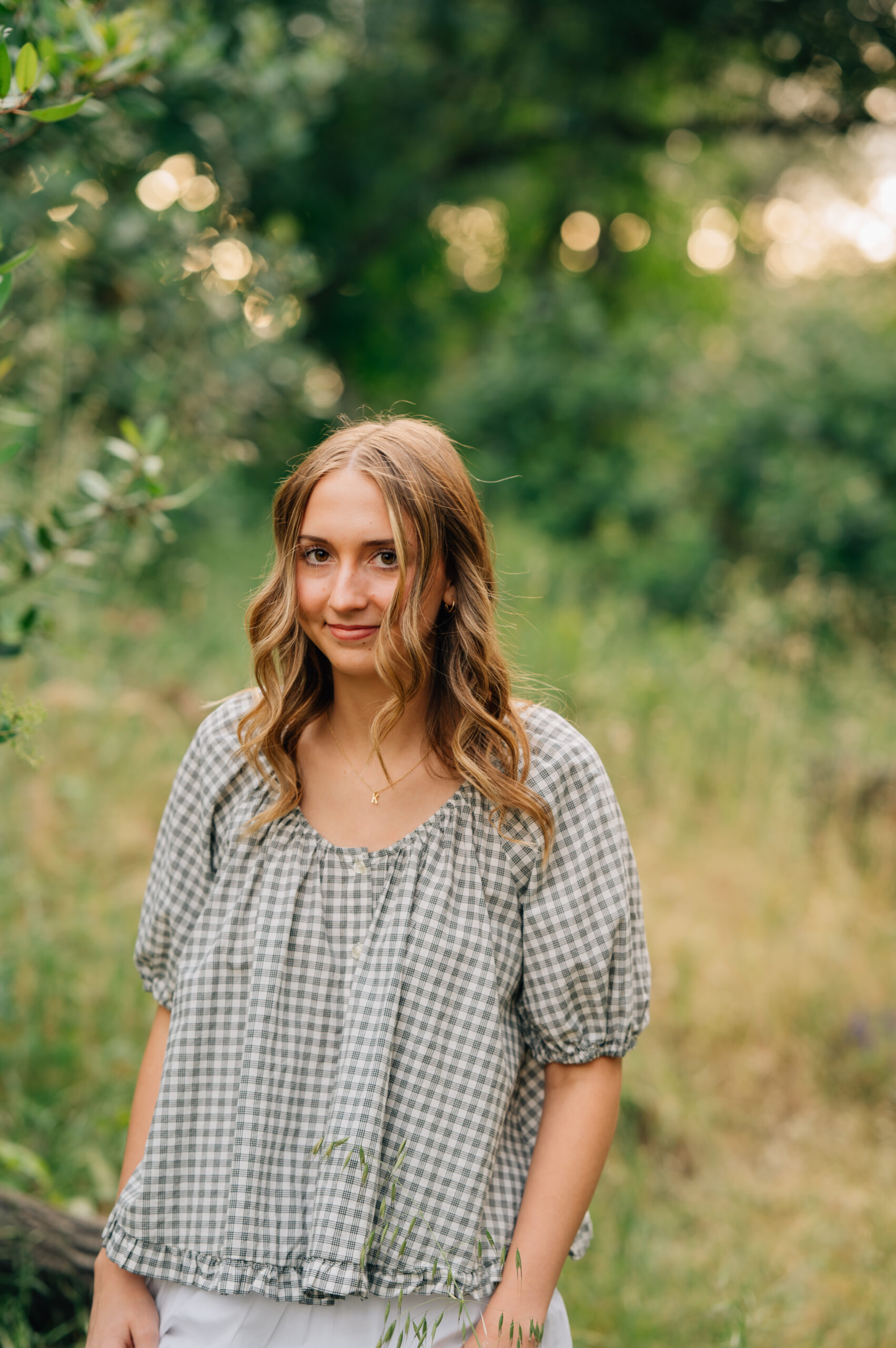 Close-up senior portrait of high school graduate smiling in soft golden evening light at Griffith Quarry Park.
