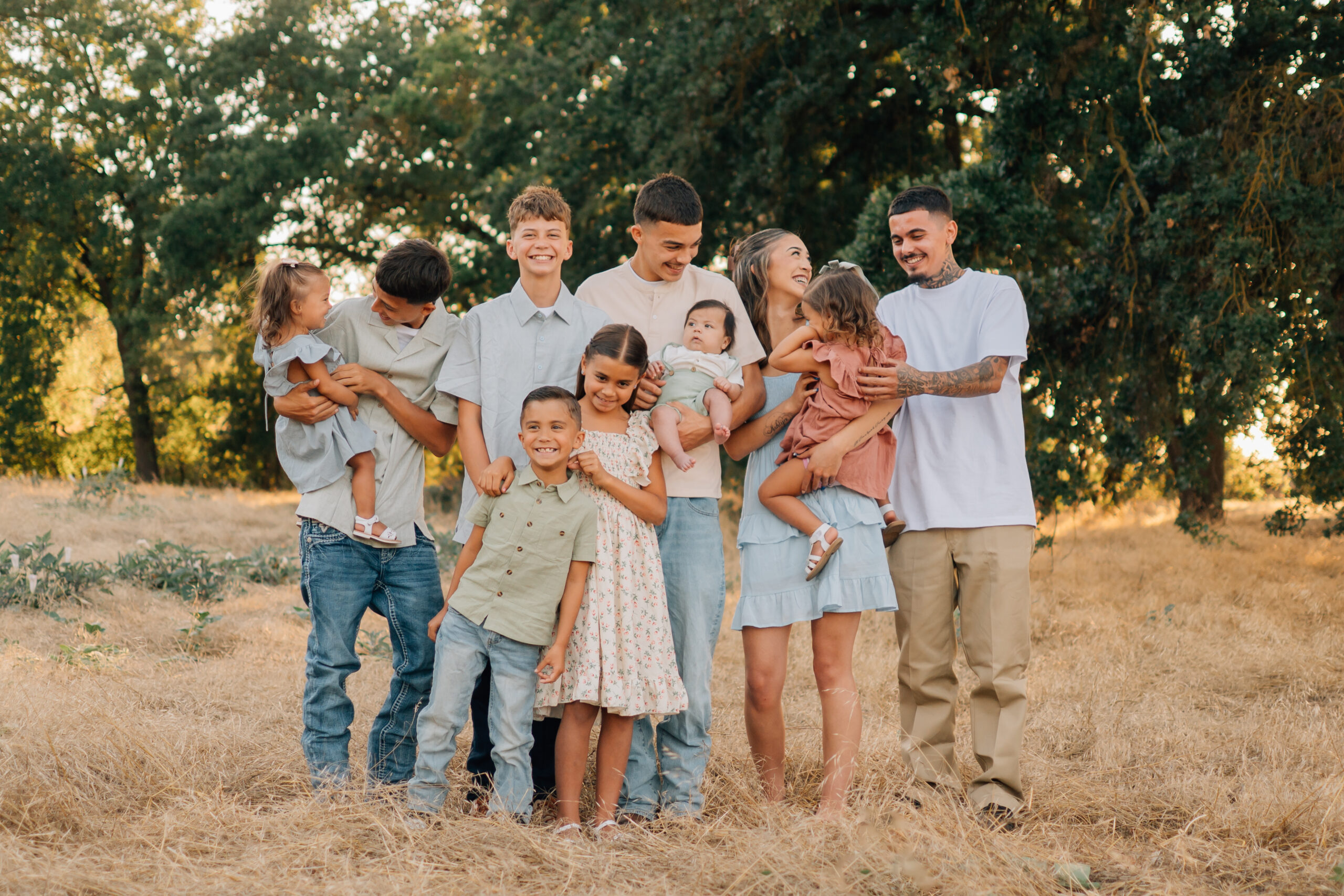 Siblings laughing, teasing, and holding the younger children during a relaxed extended family photo shoot.