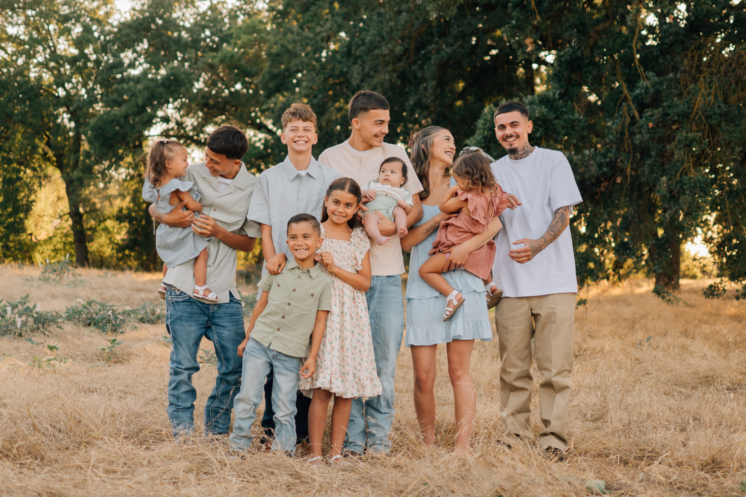 Siblings laughing, teasing, and holding the younger children during a relaxed extended family photo shoot.