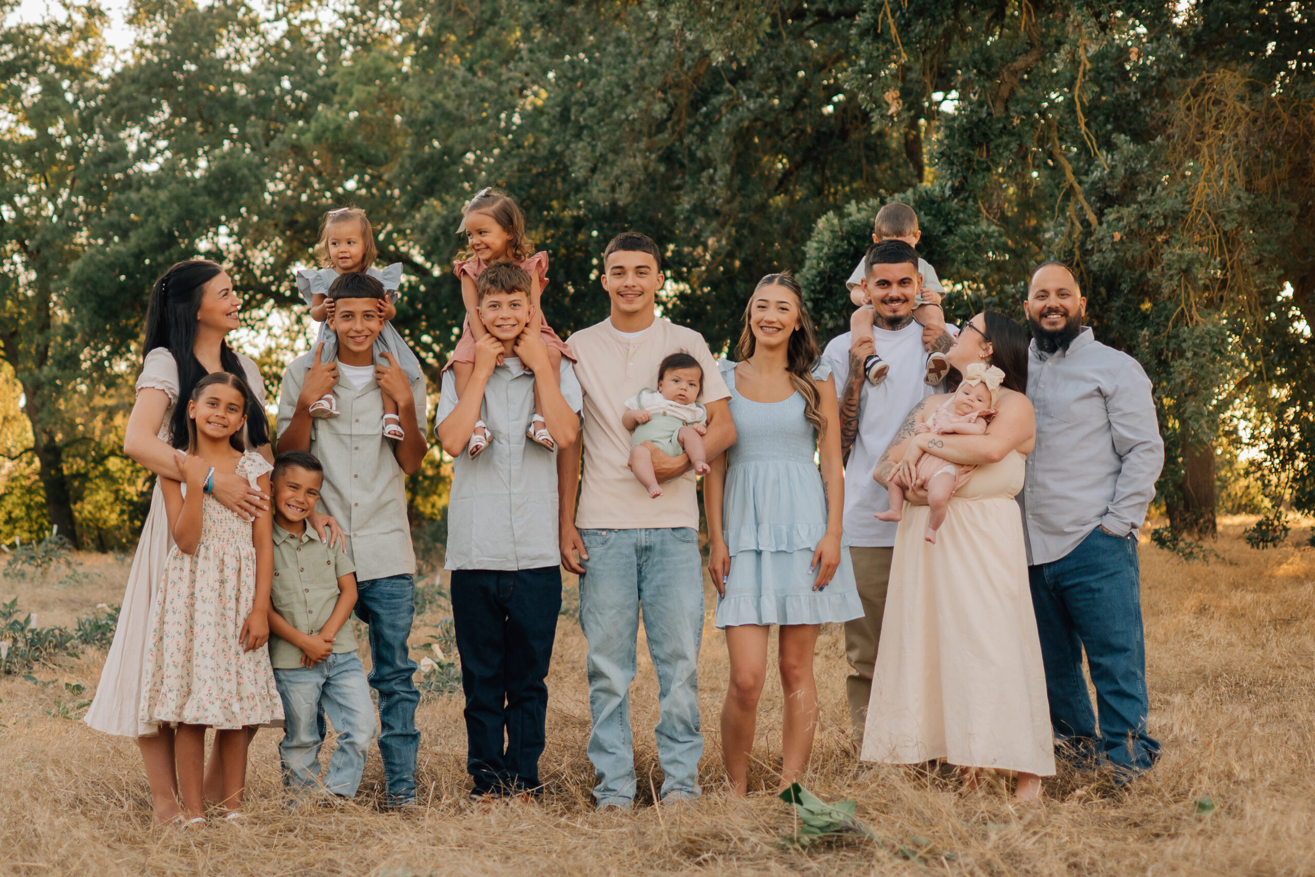 Large extended family laughing and interacting together in a sunlit field at Oak Grove Park in Ripon.