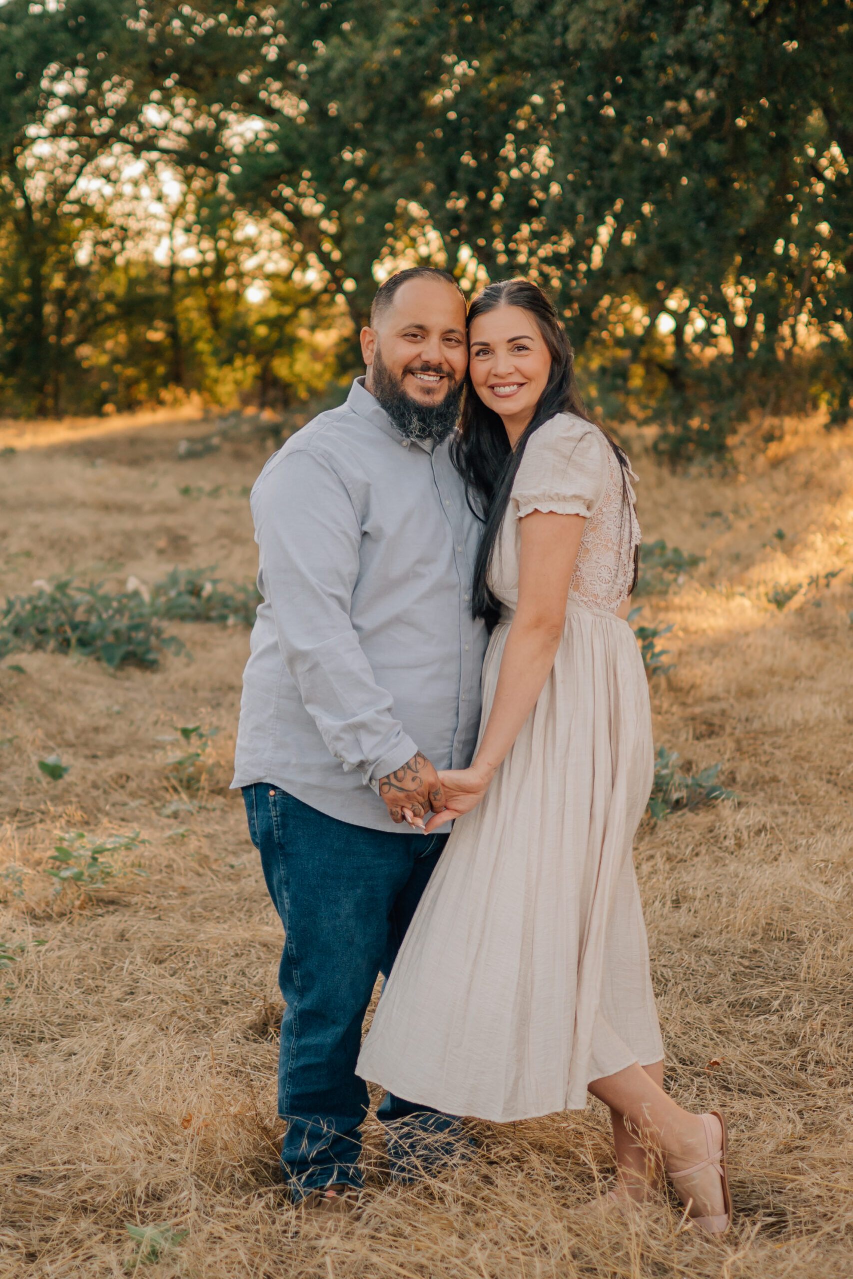 Married couple holding hands and smiling together during their family photography session at Oak Grove Park.