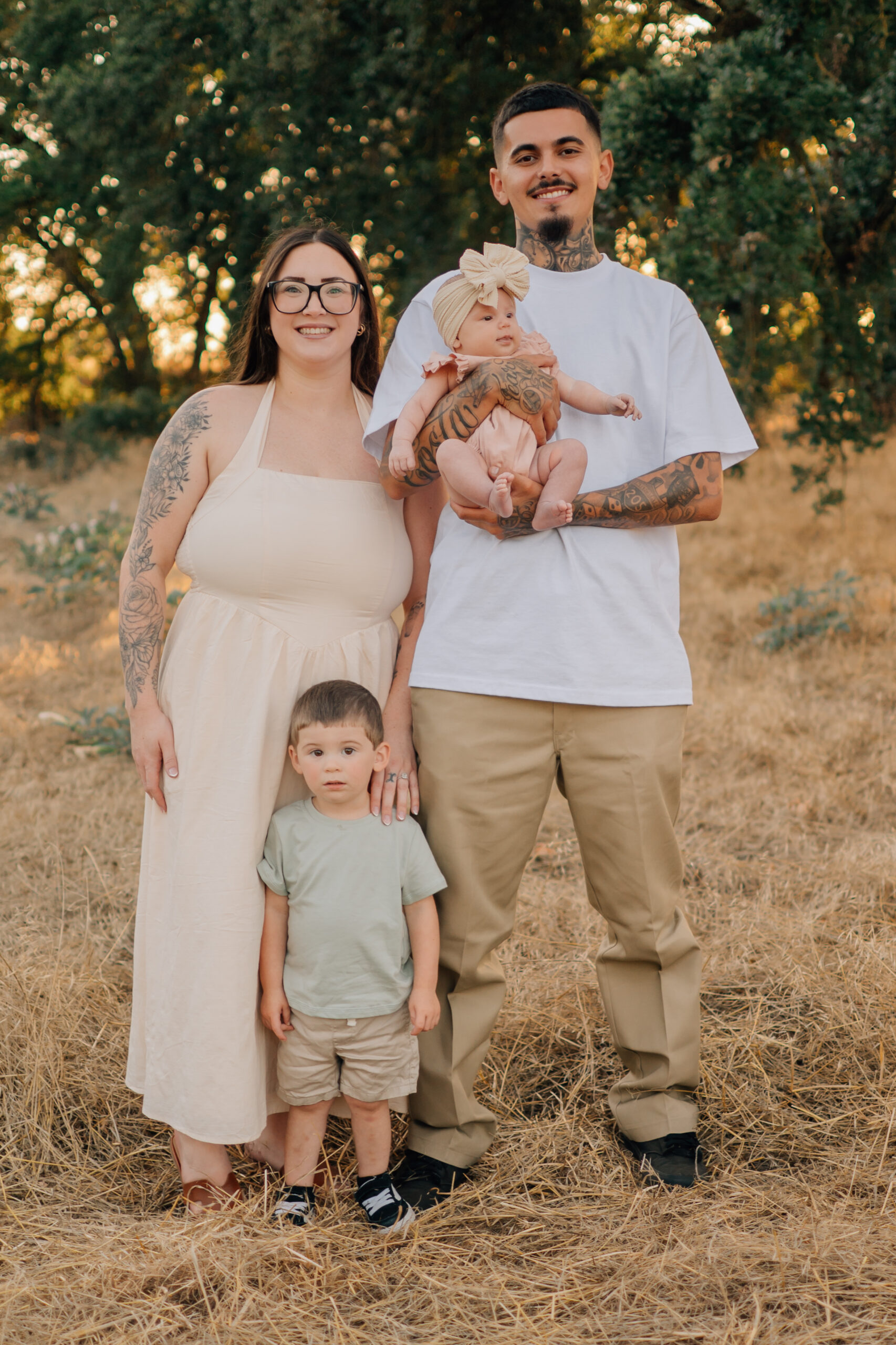 Parents holding their baby and young son during an outdoor family portrait session in a golden field.