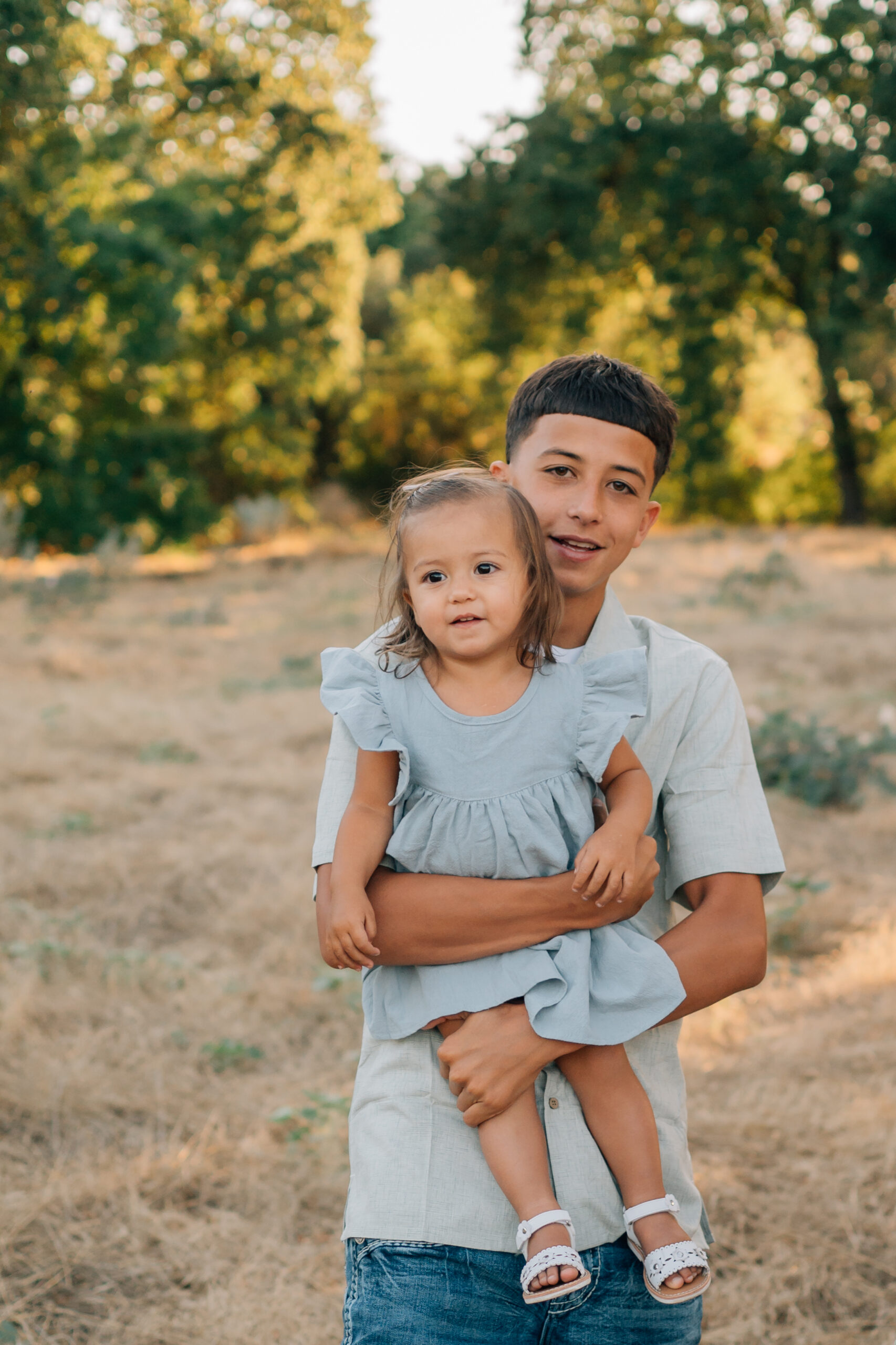 Older siblings holding toddlers and babies during a warm, candid family photo session.