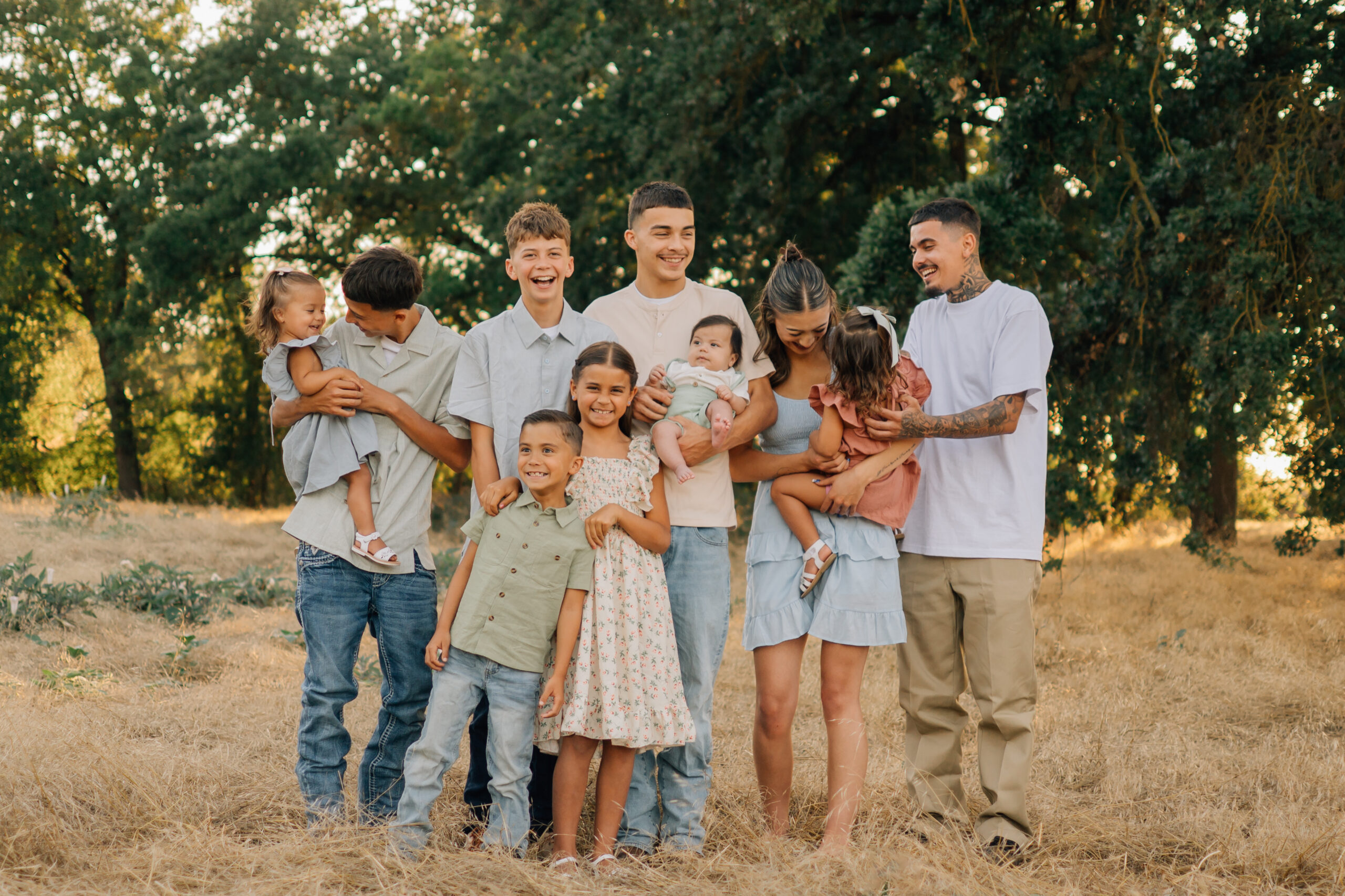 Siblings laughing, teasing, and holding the younger children during a relaxed extended family photo shoot.
