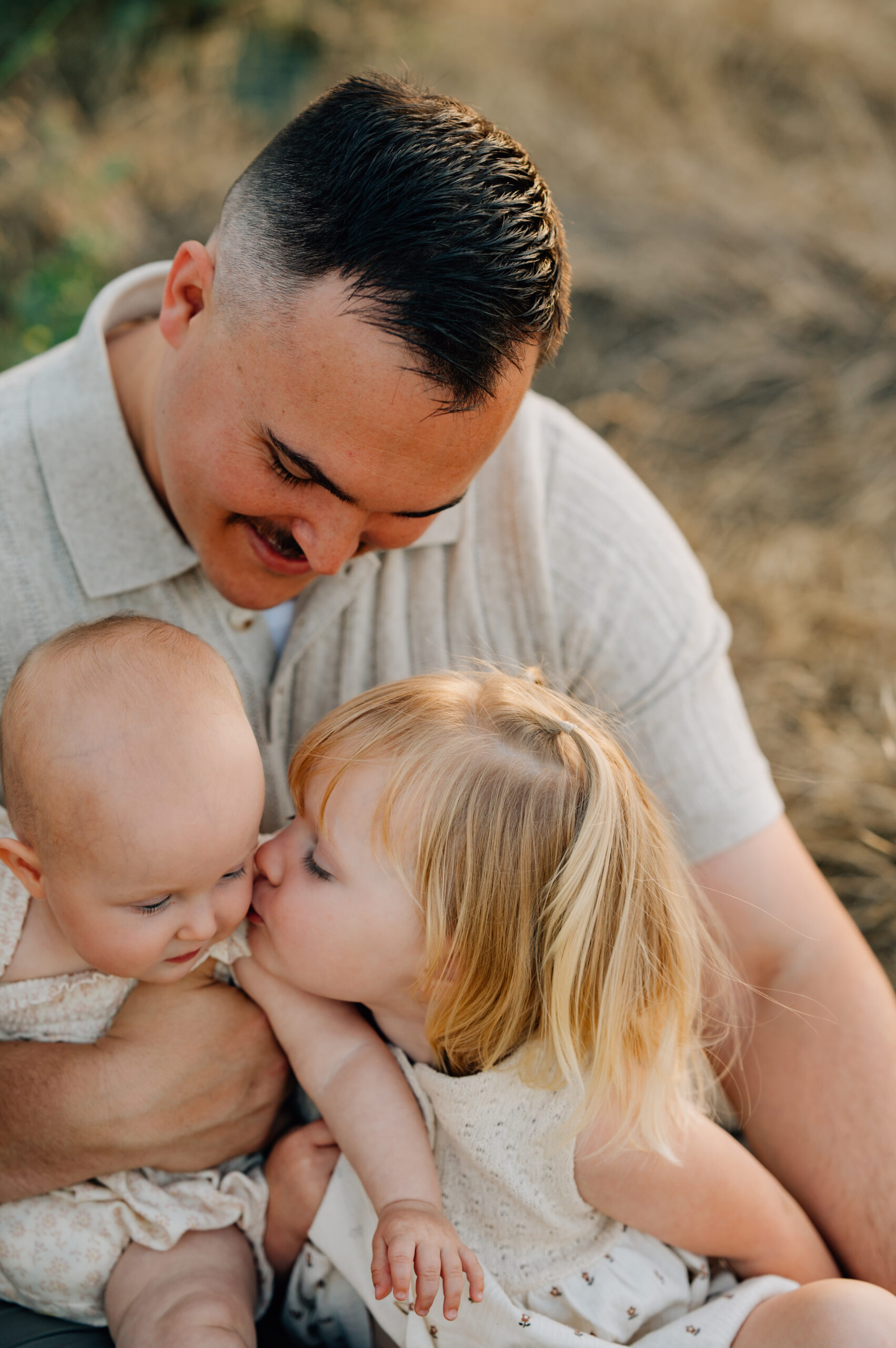 Big sister kissing her baby twin sisters during a candid family photography session in Ripon.