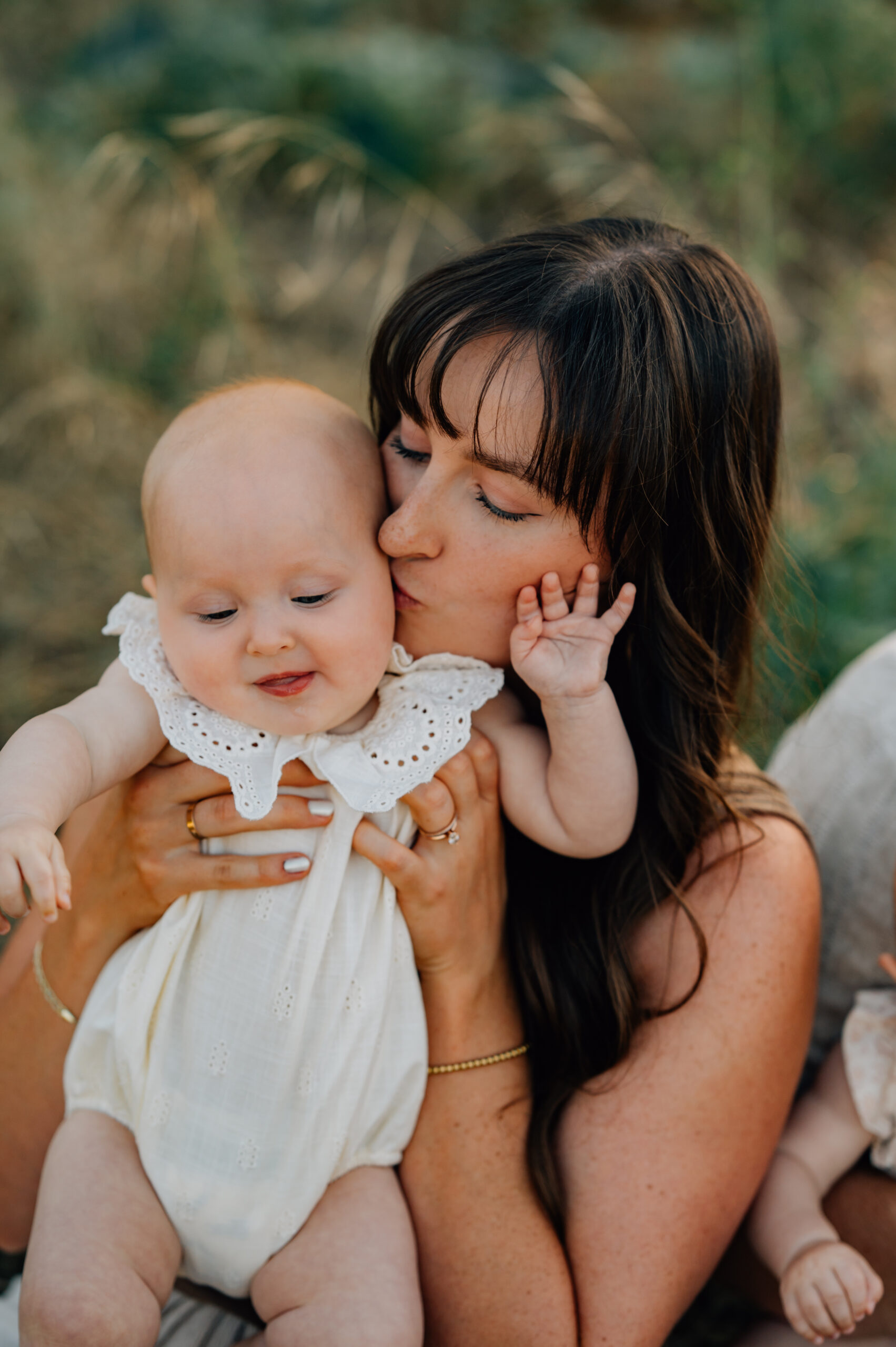 Mom kissing her daughters cheek during a family photography session at Oak Grove Park.