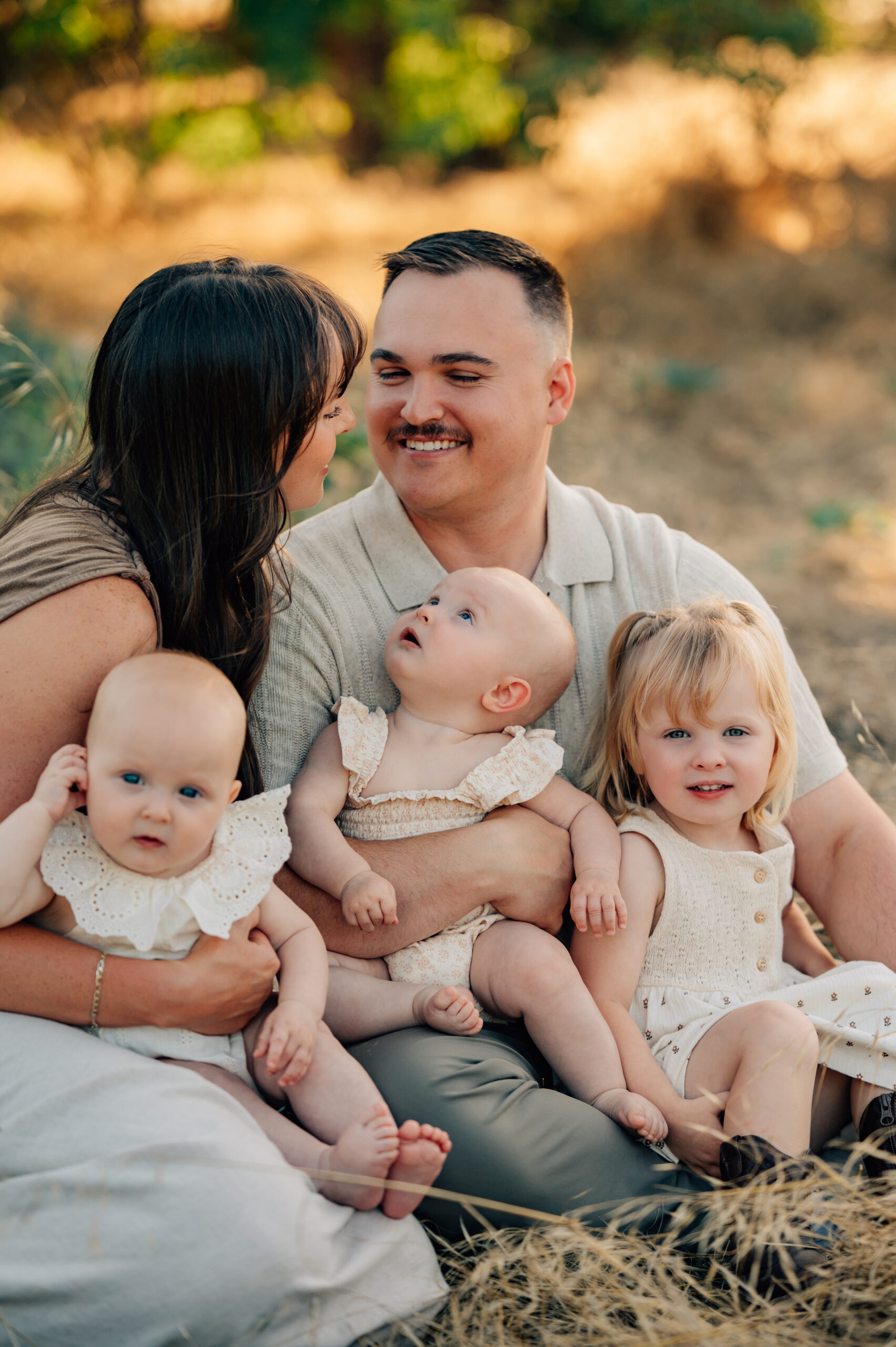 Family of five sitting together in a grassy field during a relaxed outdoor family session at Oak Grove Park.