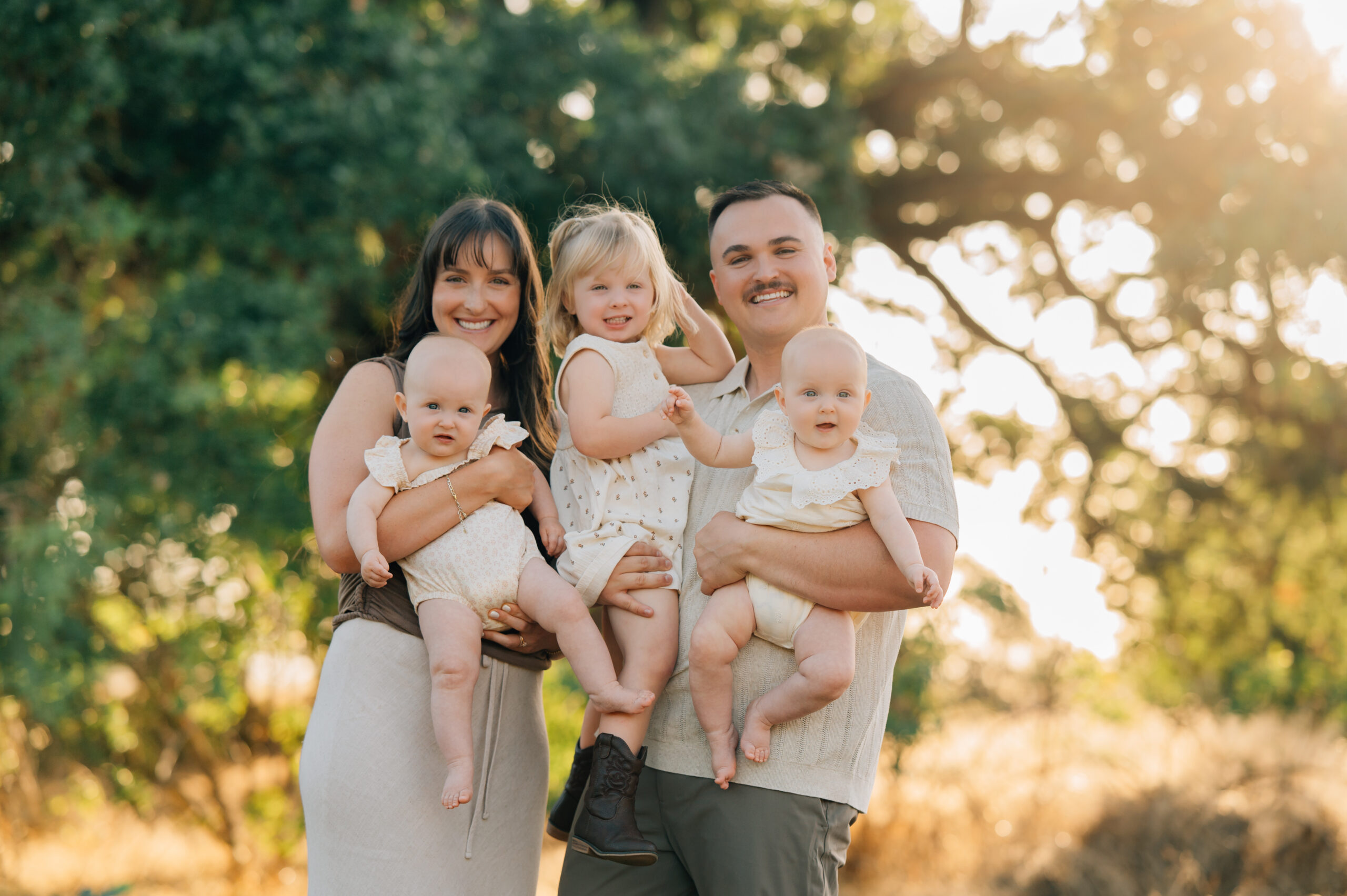 Family of five standing together in golden sunset light during a dreamy outdoor family photography session.
