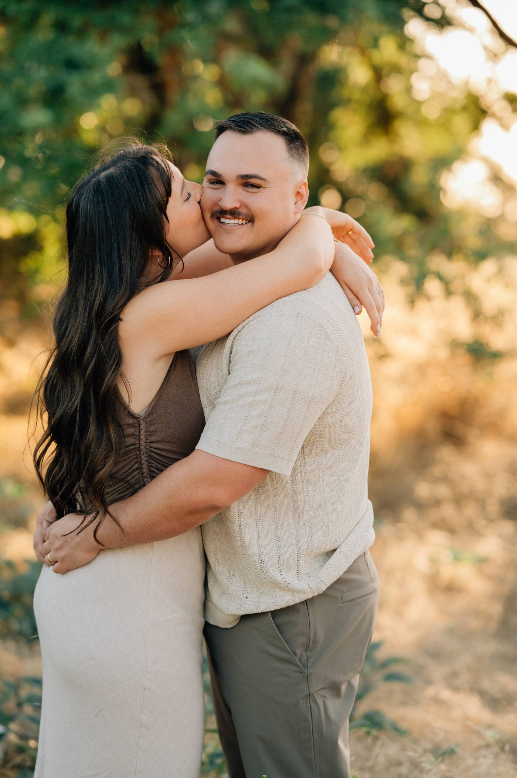 Husband and wife sharing a smile while holding their daughters during an outdoor family photography session.