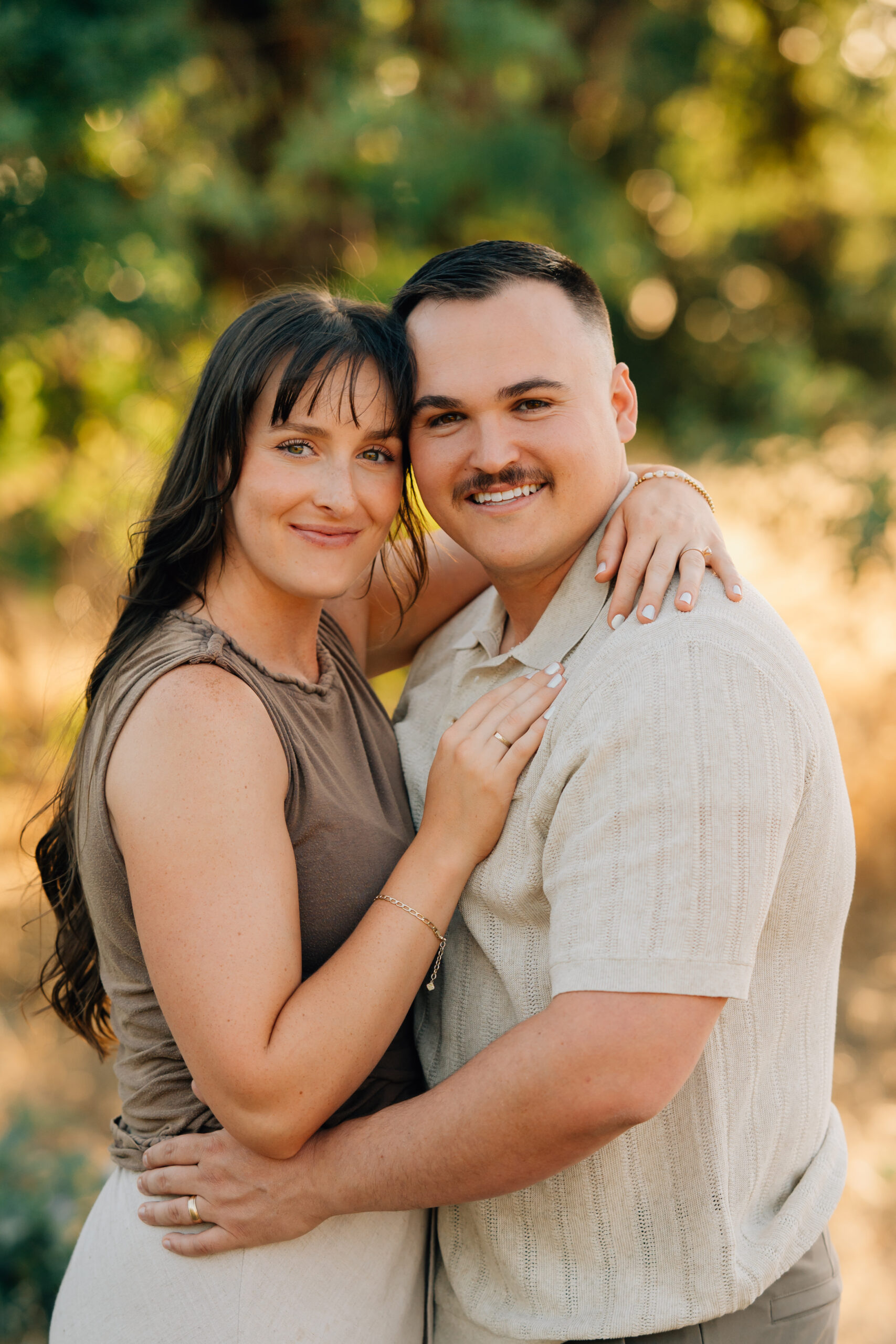 Husband and wife sharing a smile while holding their daughters during an outdoor family photography session.