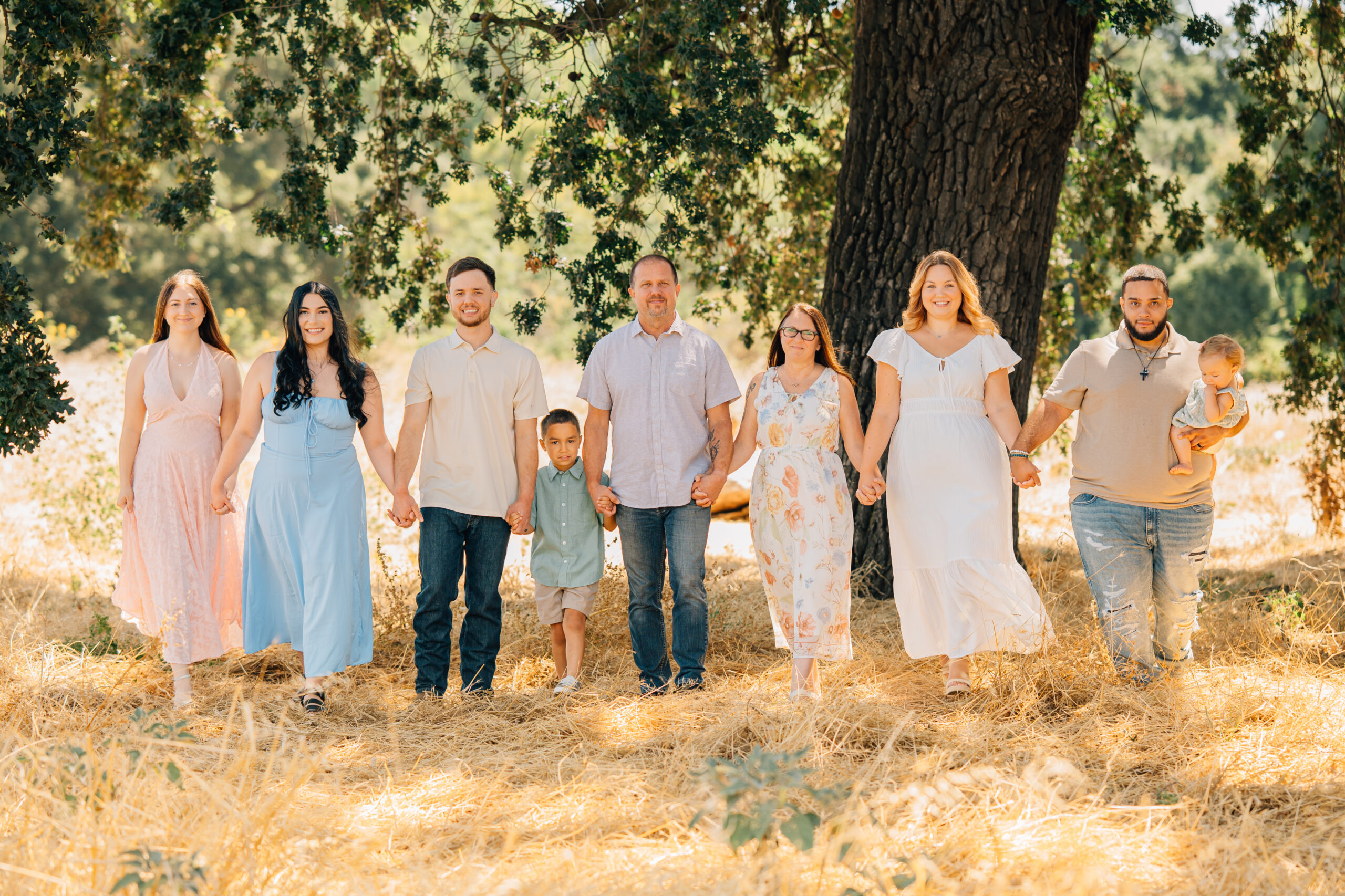 Extended family walking under an oak tree during session. 