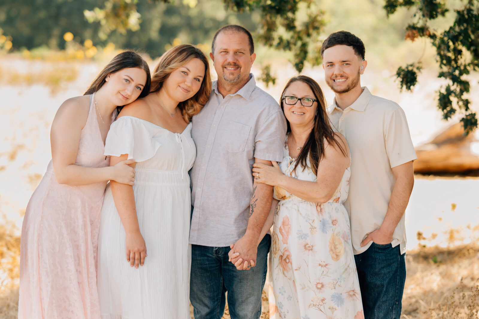 A family of five posing under an oak tree during an extended family session at Army Corps Park. 